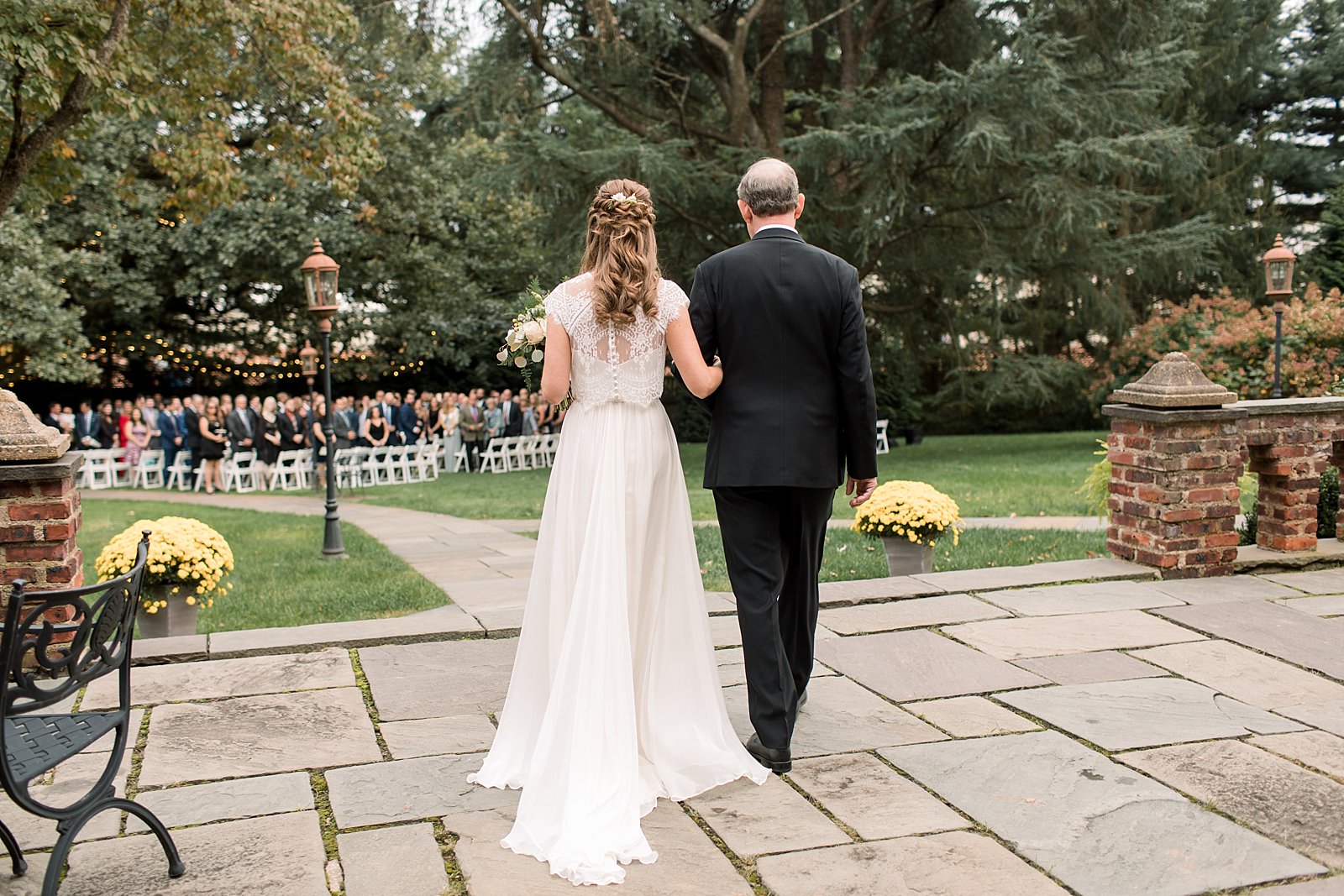 bride and groom walk across patio for wedding ceremony at Aldie Mansion