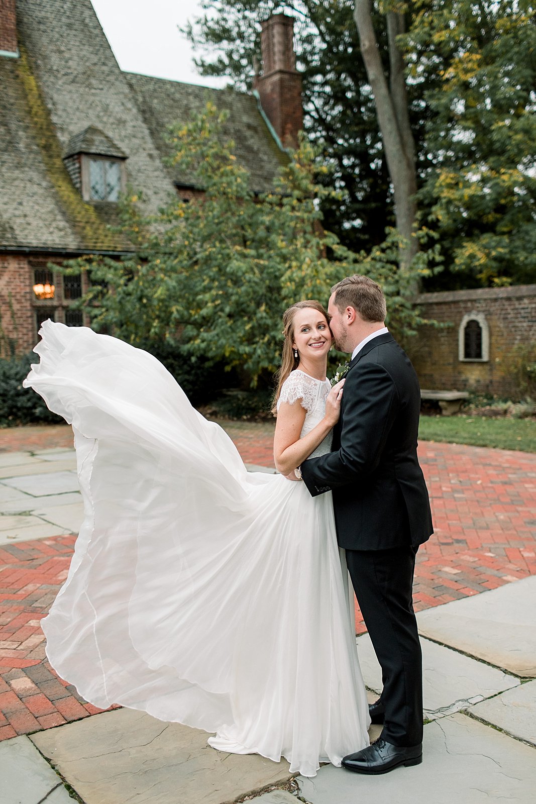 groom kisses bride's cheek with dress floating behind them at Aldie Mansion