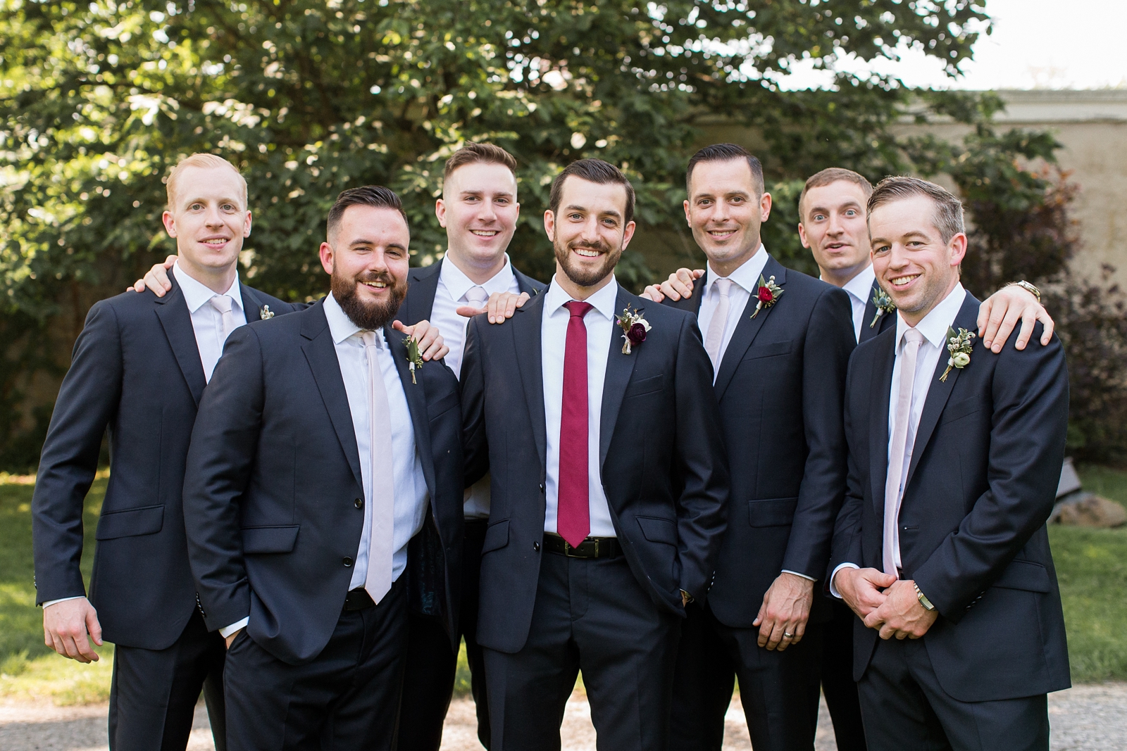 groom poses with groomsmen in navy suits at The Carriage House at Rockwood Park