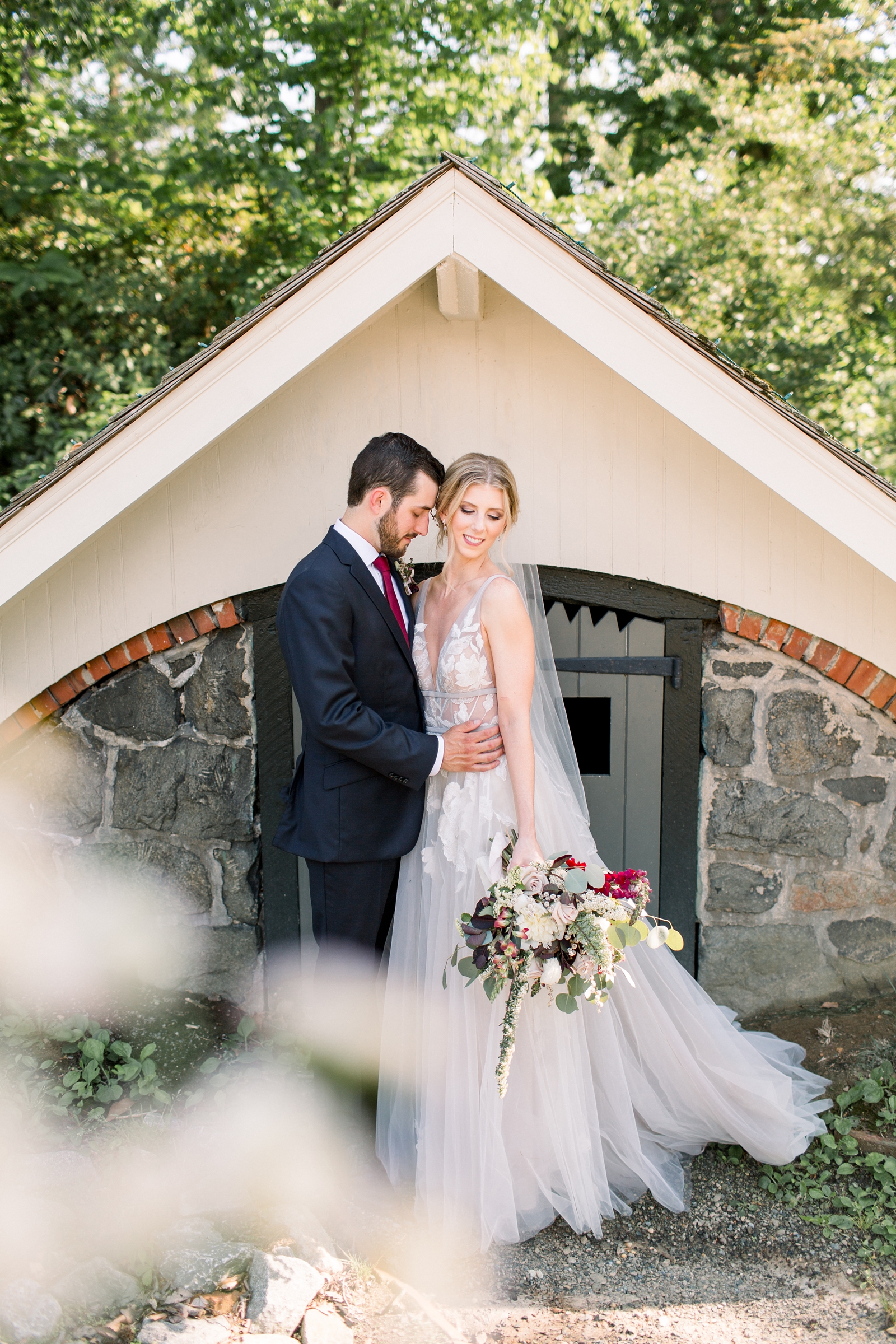 newlyweds hug by stone building at The Carriage House at Rockwood Park
