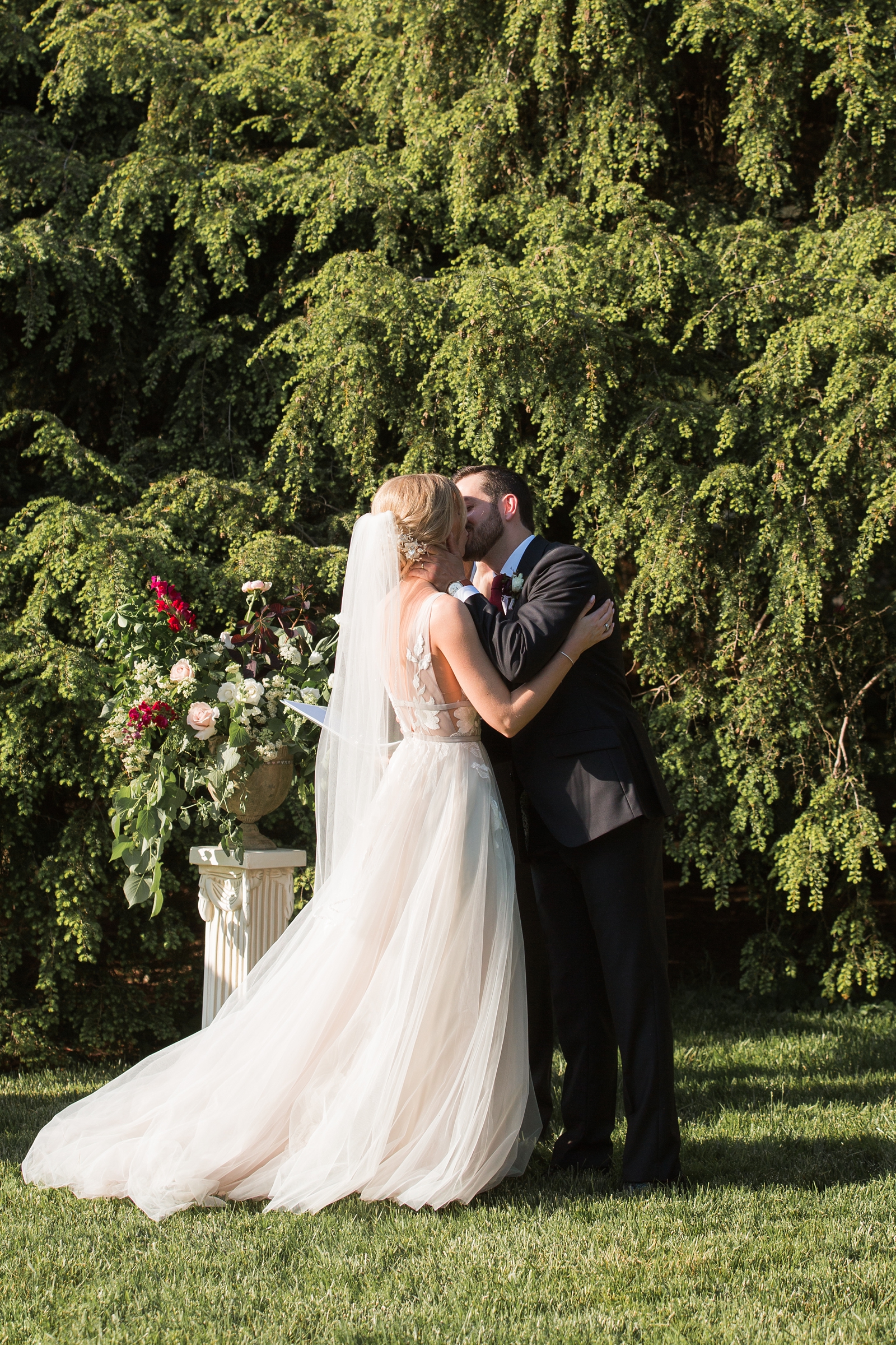 newlyweds kiss after lawn wedding ceremony at The Carriage House at Rockwood Park