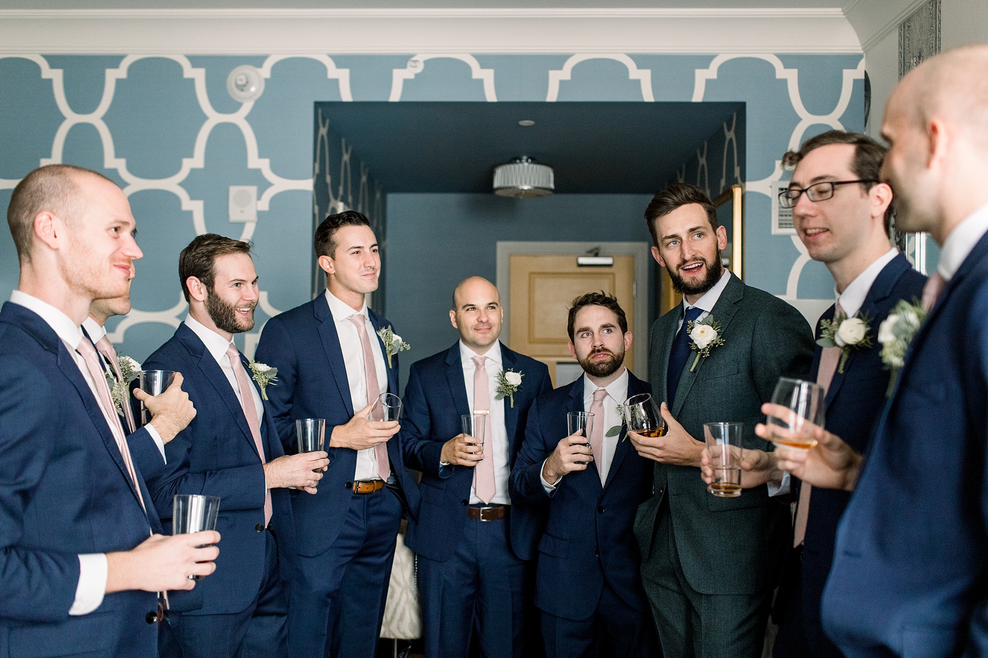 groom stands with groomsmen listening to toast 