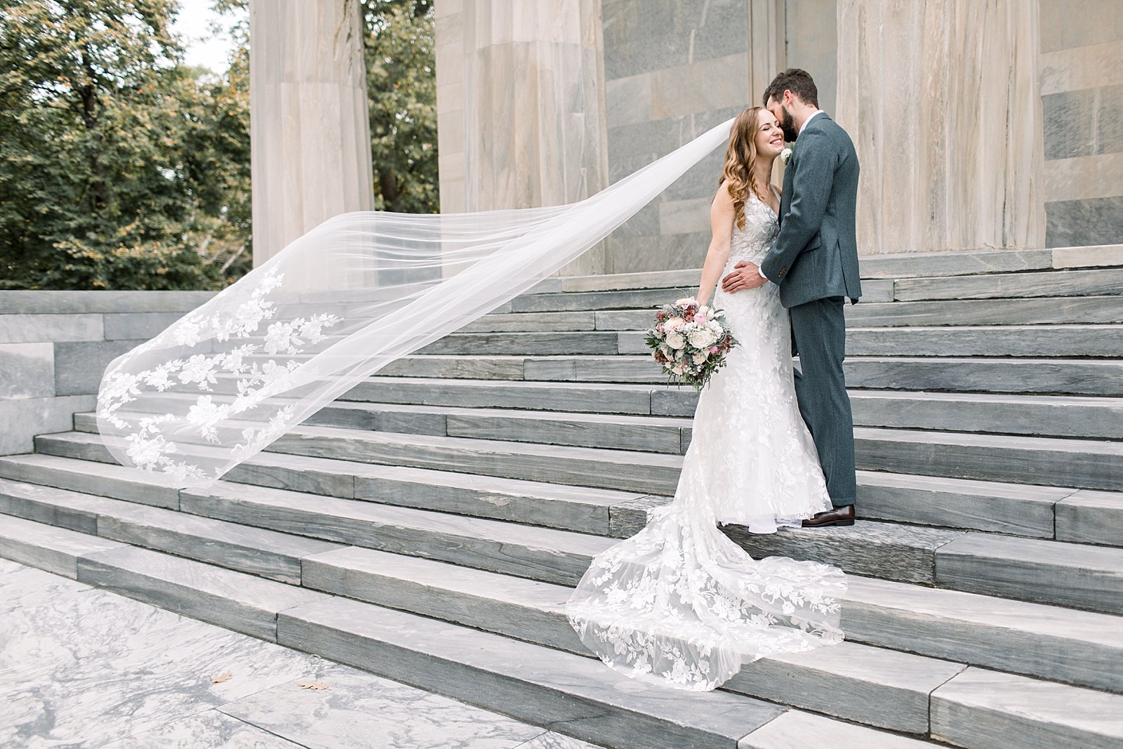 groom leans to kiss bride's cheek on steps of the Merchant’s Exchange Building
