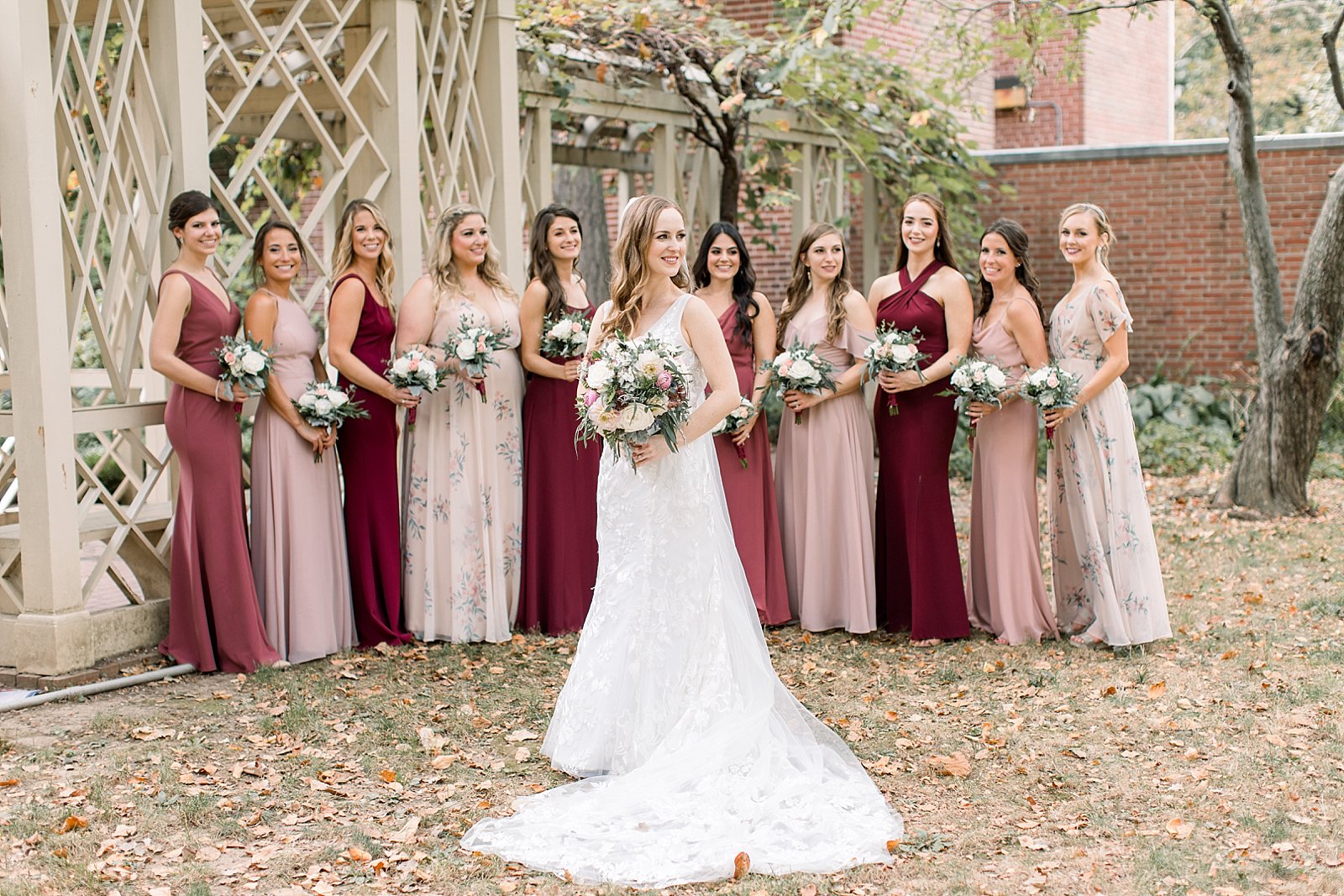 bride stands with bridesmaids in pink and red mismatched gowns at the Merchant’s Exchange Building