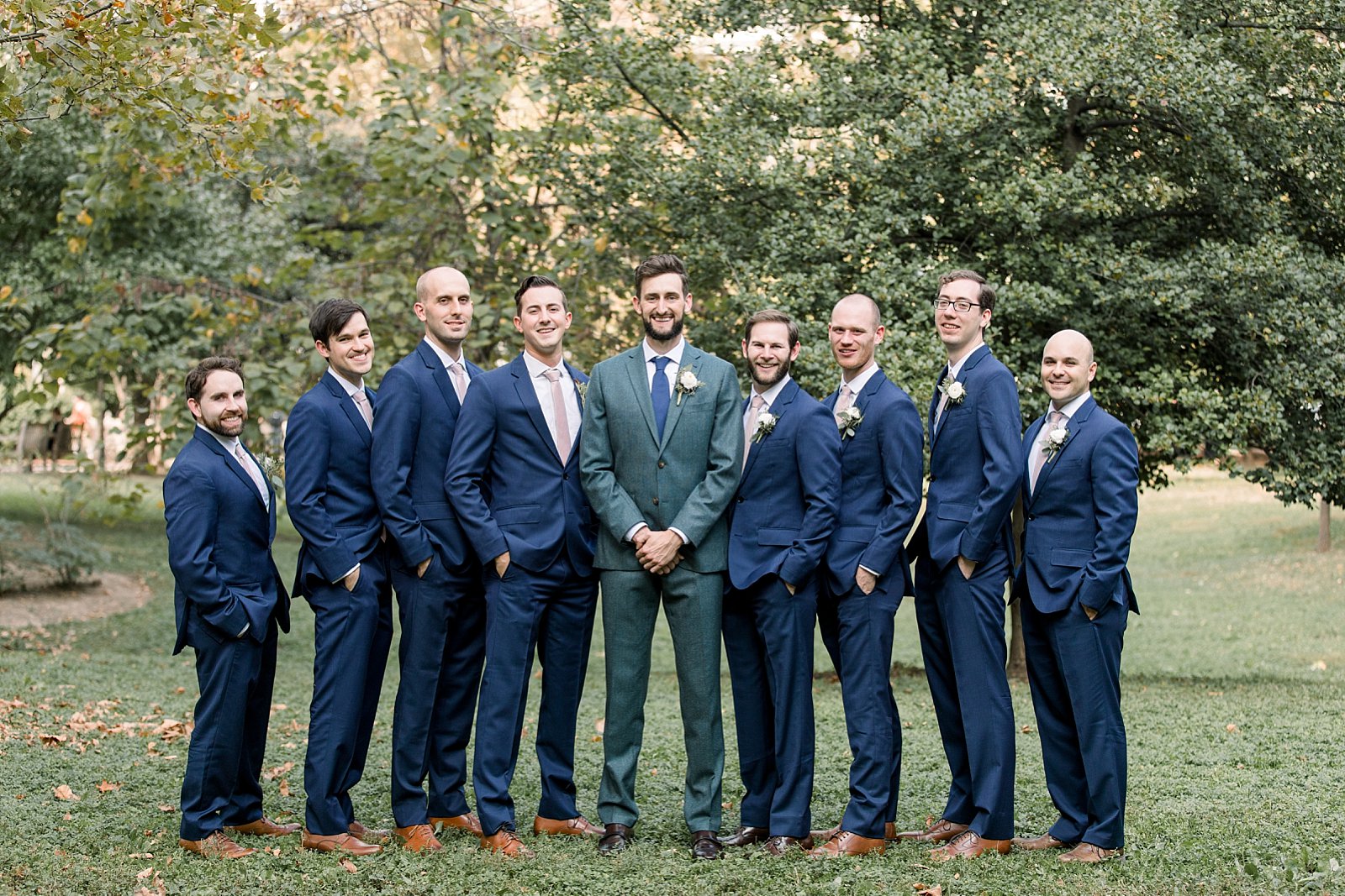 groom stands with groomsmen in navy suits with pink ties 