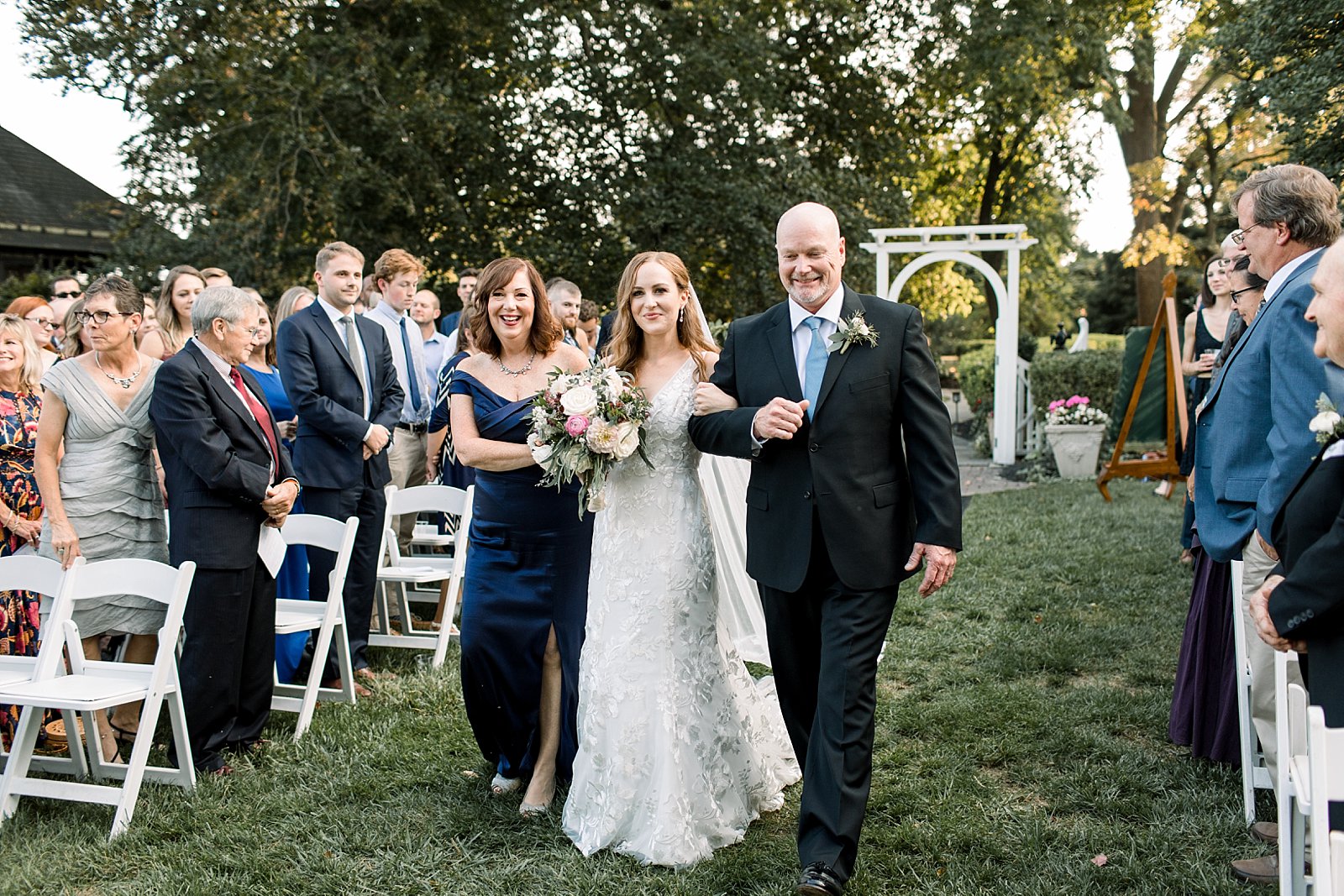 bride tears up walking down aisle with parents during Knowlton Mansion wedding ceremony on the lawn