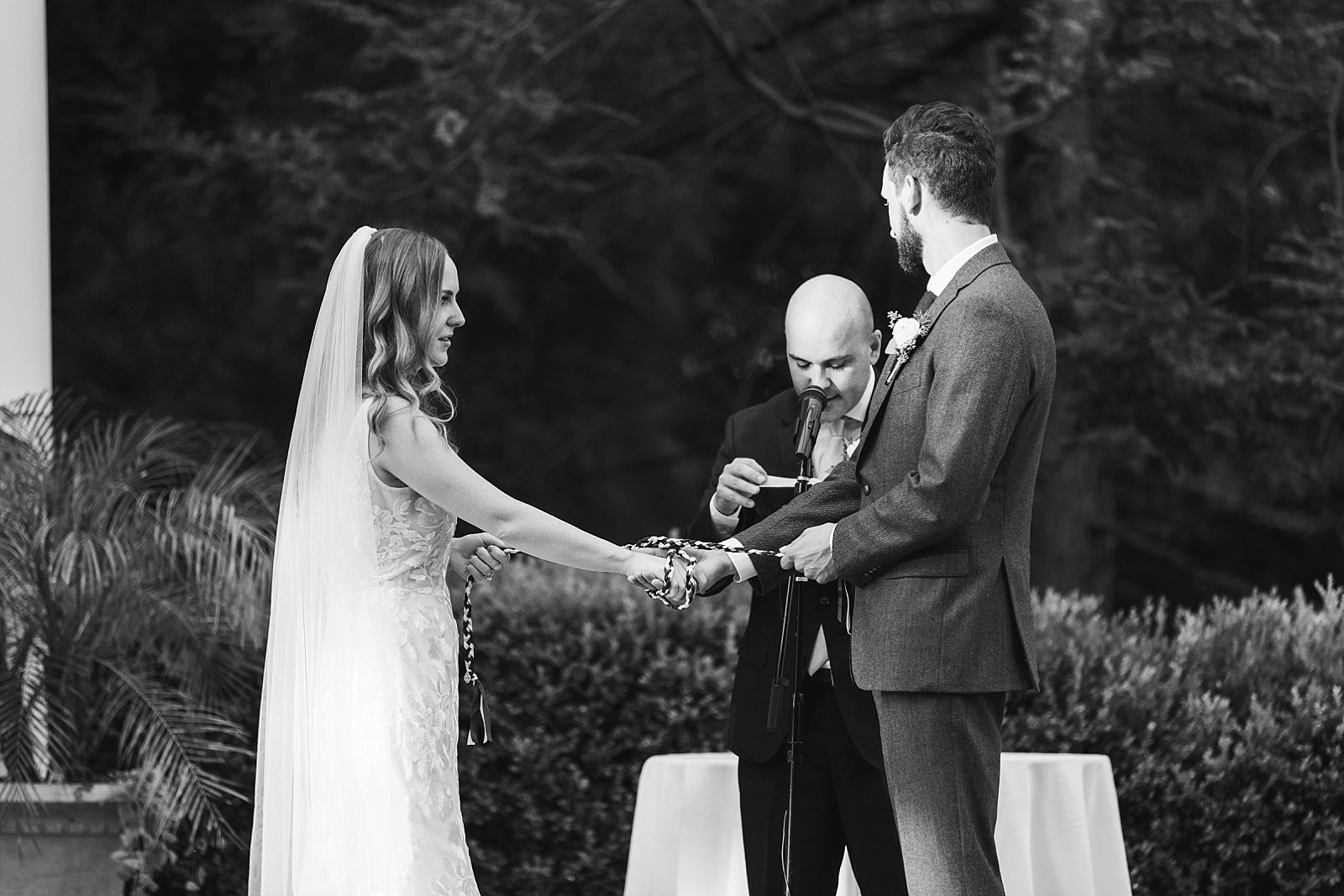 bride and groom hold hands during hand fasting ceremony 