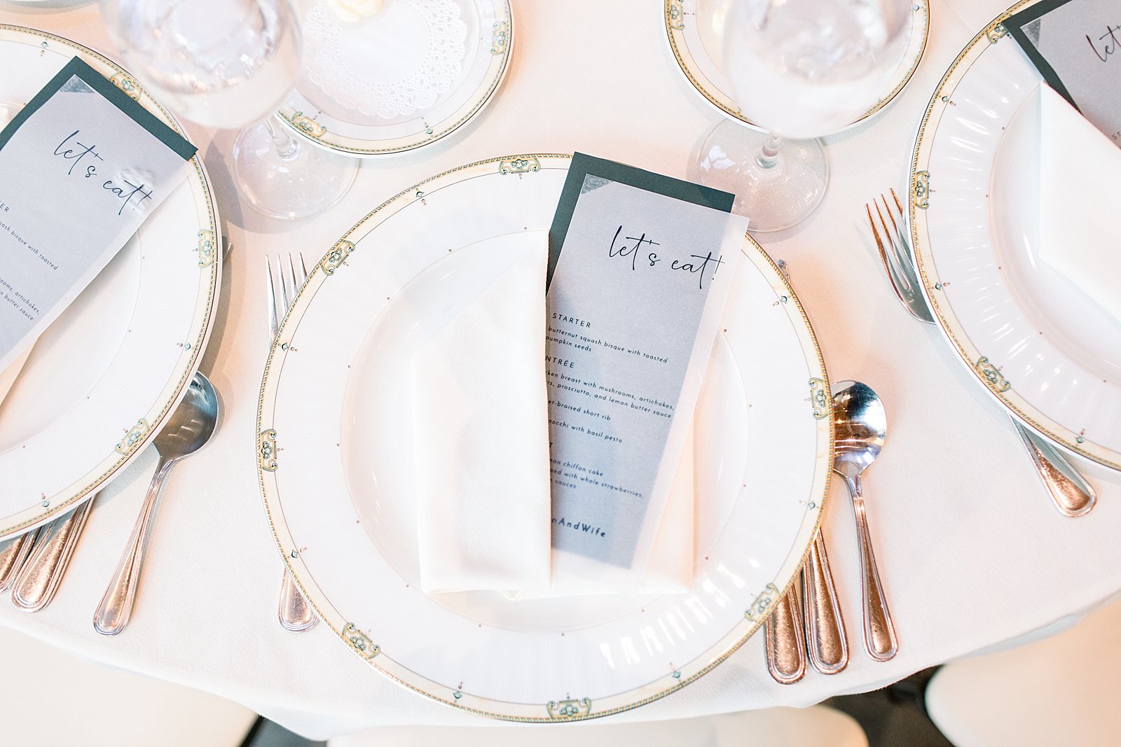place setting with vellum menu card on white plate with gold rim 