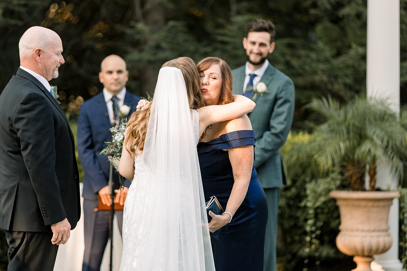 mother in blue dress hugs bride during ceremony 