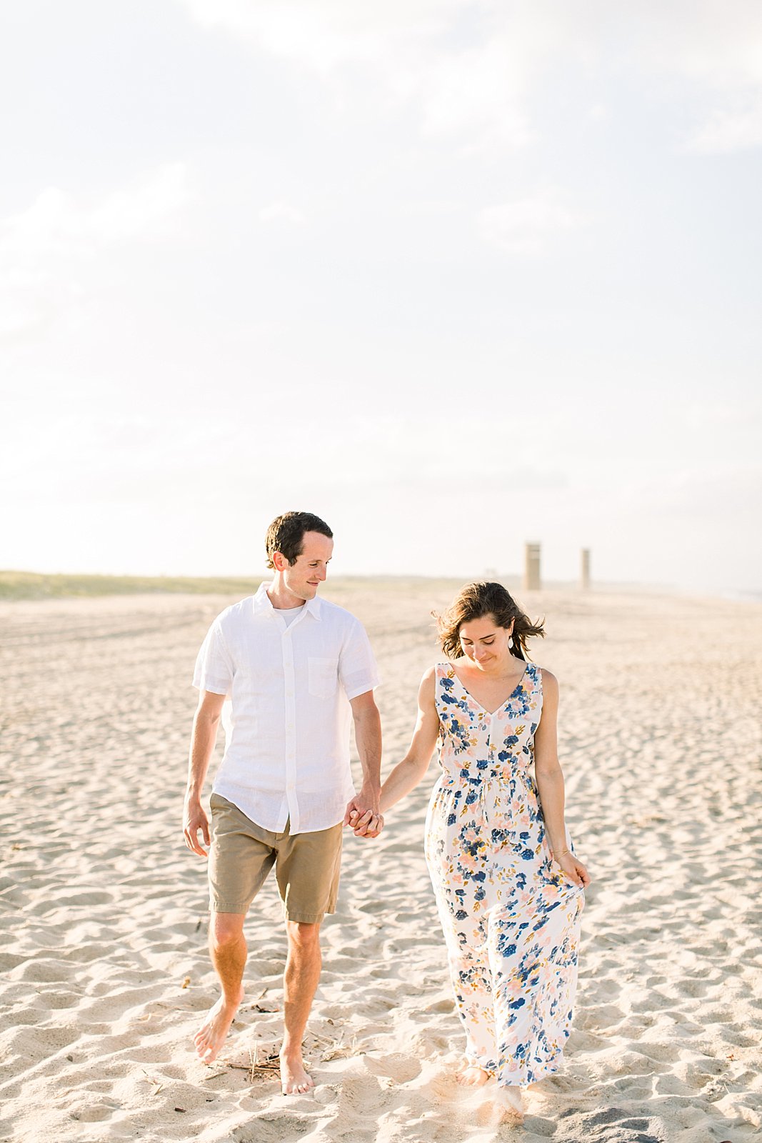 engaged couple holds hands walking on beach during engagementphotos 