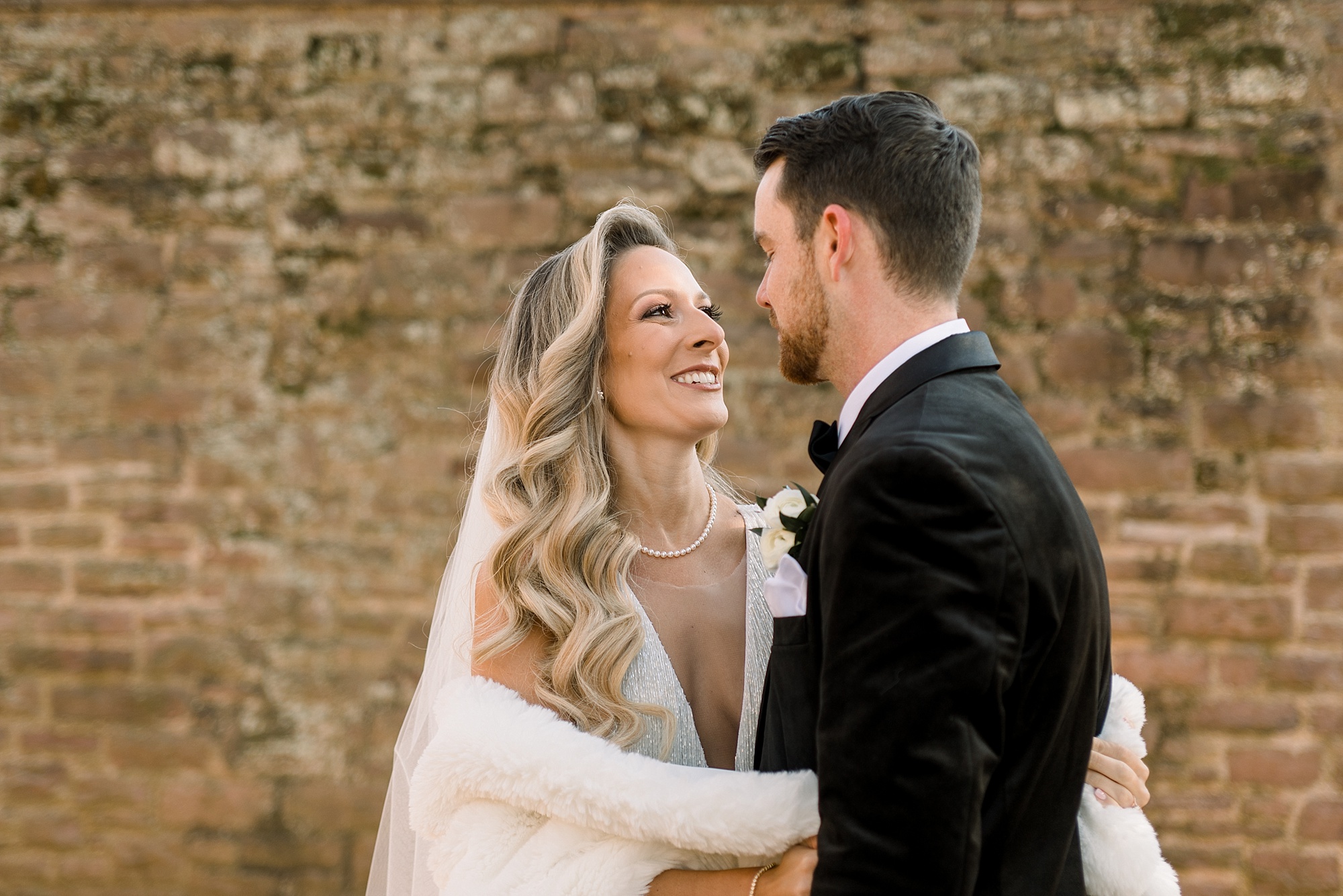 bride in fringe wedding dress smiles up at groom in velvet suit 
