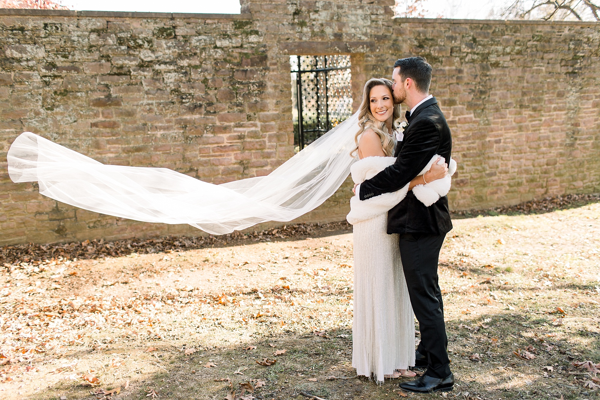 groom kisses bride with veil floating behind them at Tyler Gardens 