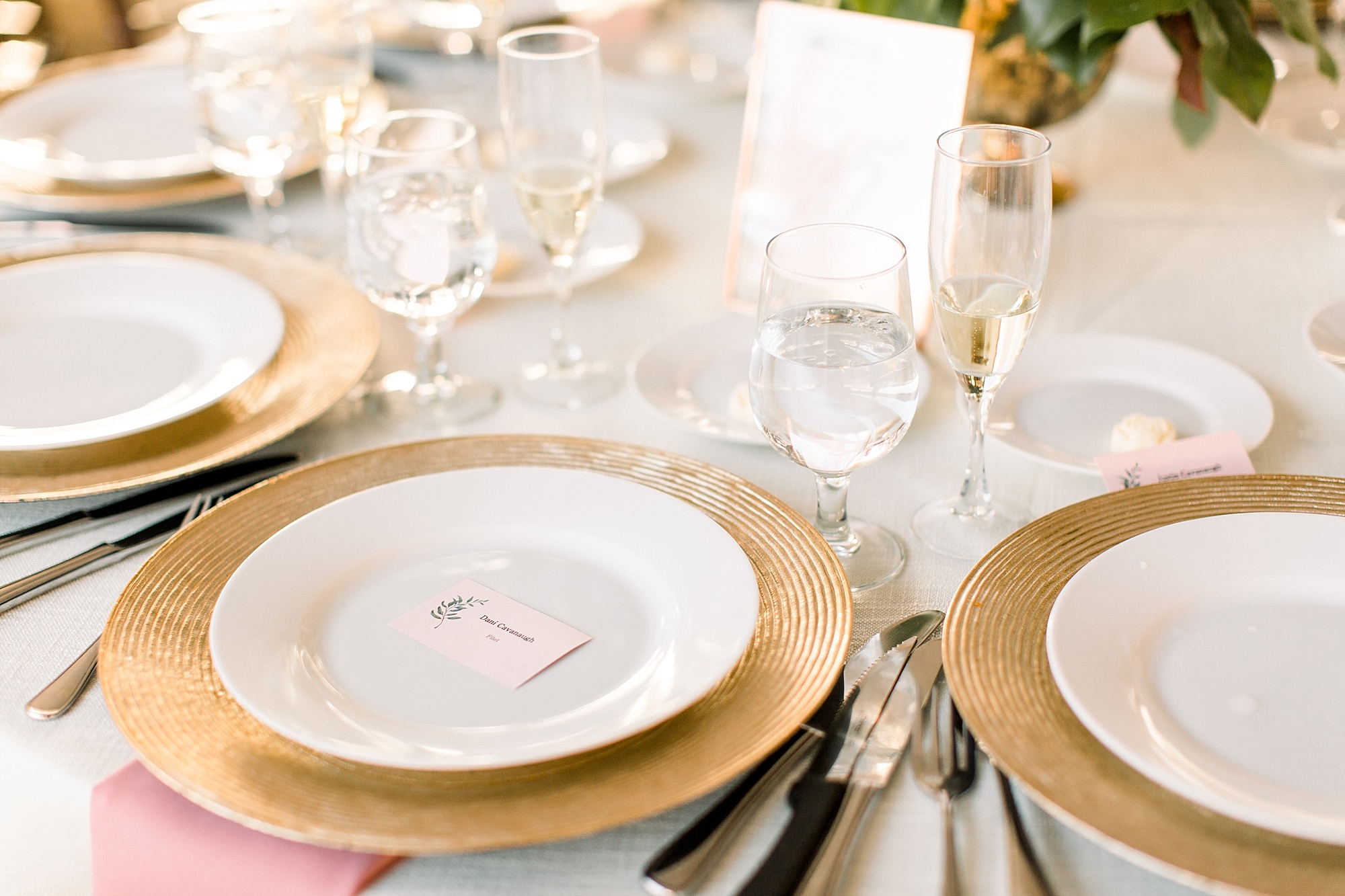 Tyler Gardens wedding reception with white plates on gold chargers and seating cards with greenery 