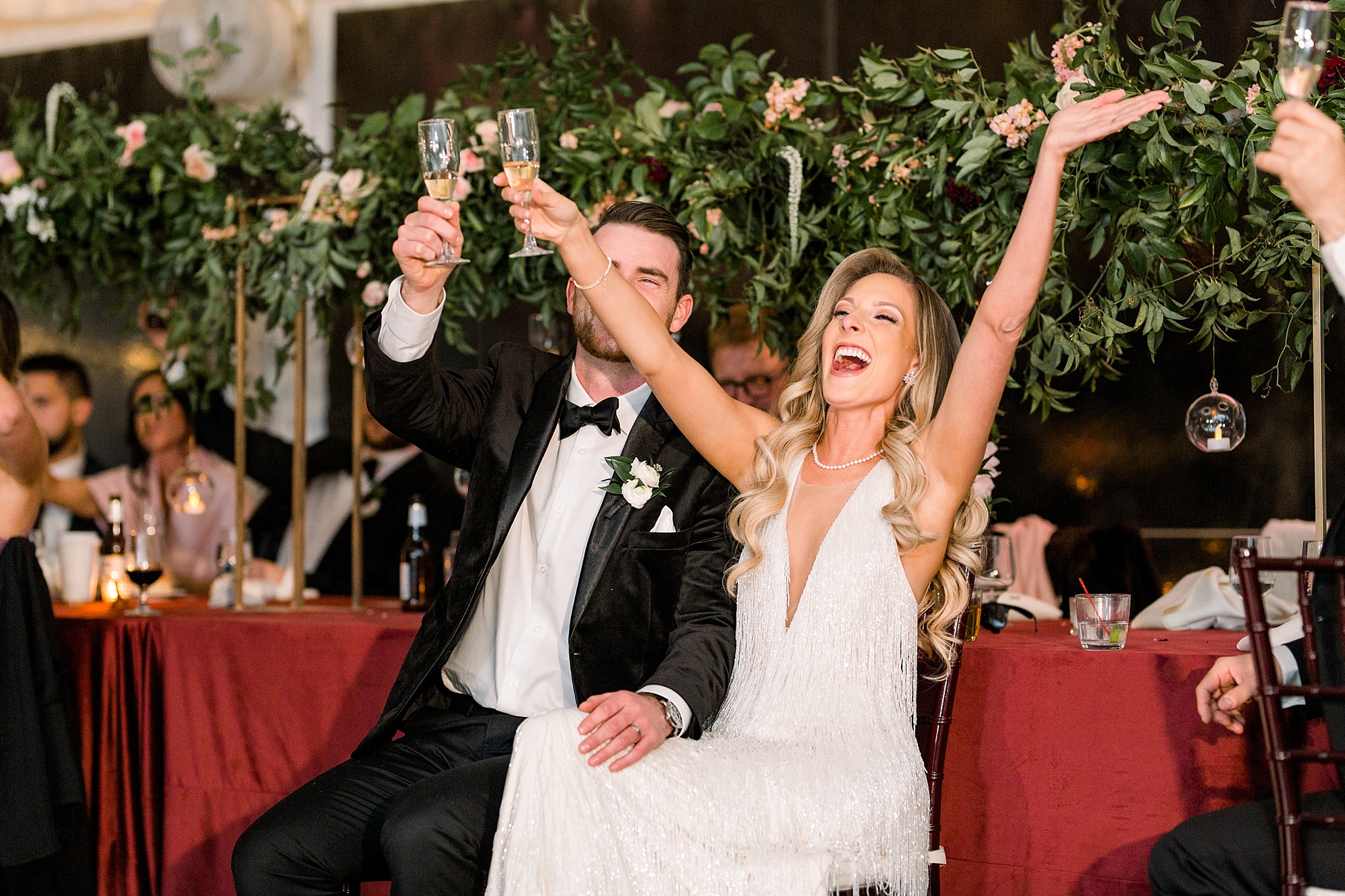 bride and groom cheer in front of head table at Tyler Gardens wedding reception