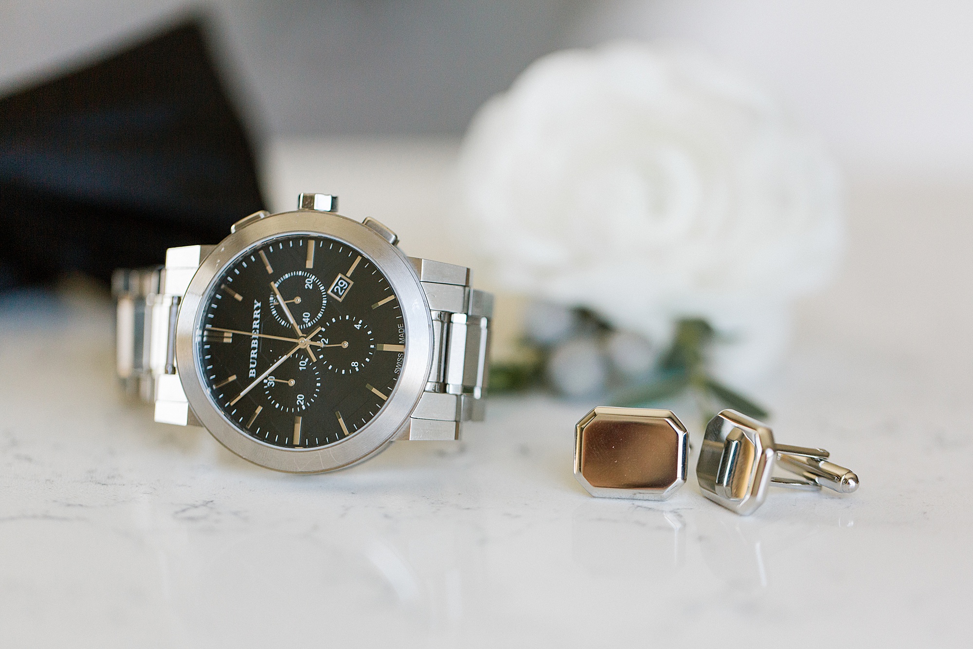 groom's watch and cufflinks lay on marble table 