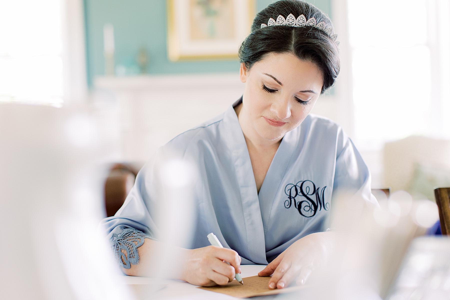 bride in blue robe writes note on wedding morning 