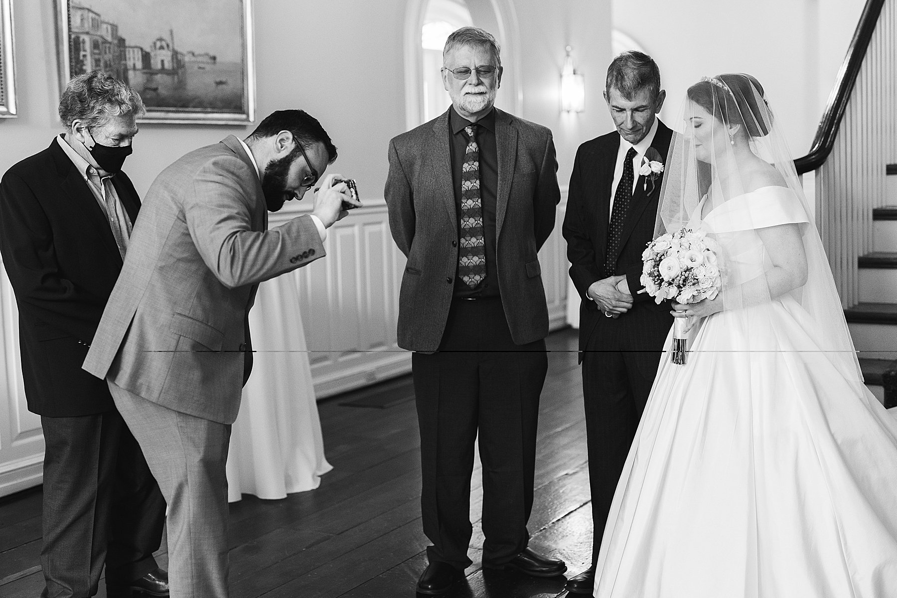 bride and father pray with guests inside Bellevue Hall
