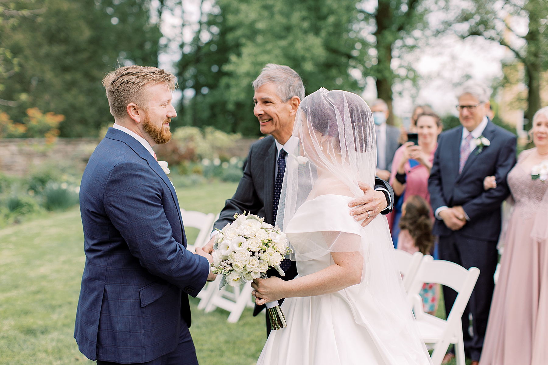 groom shakes bride's father's hand during outdoor ceremony in Delaware 