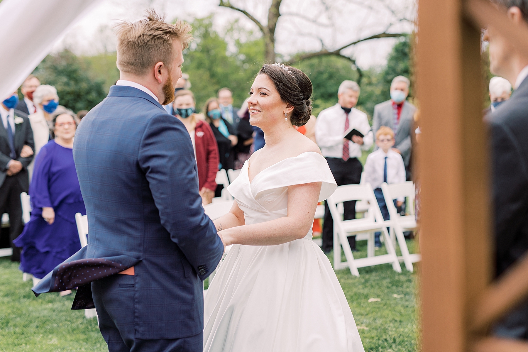 bride smiles up at groom during wedding ceremony on lawn at Bellevue Hall