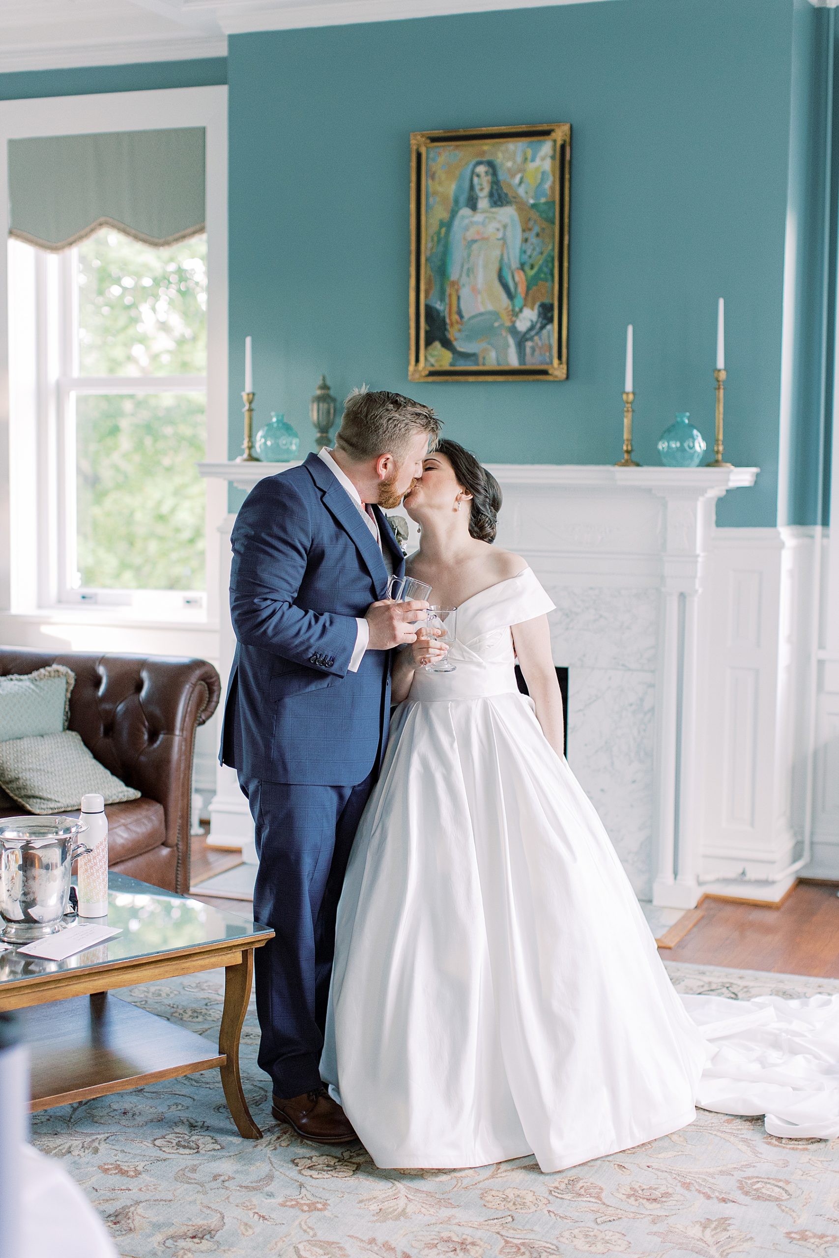 bride and groom kiss in front of teal and white wall at Bellevue Hall