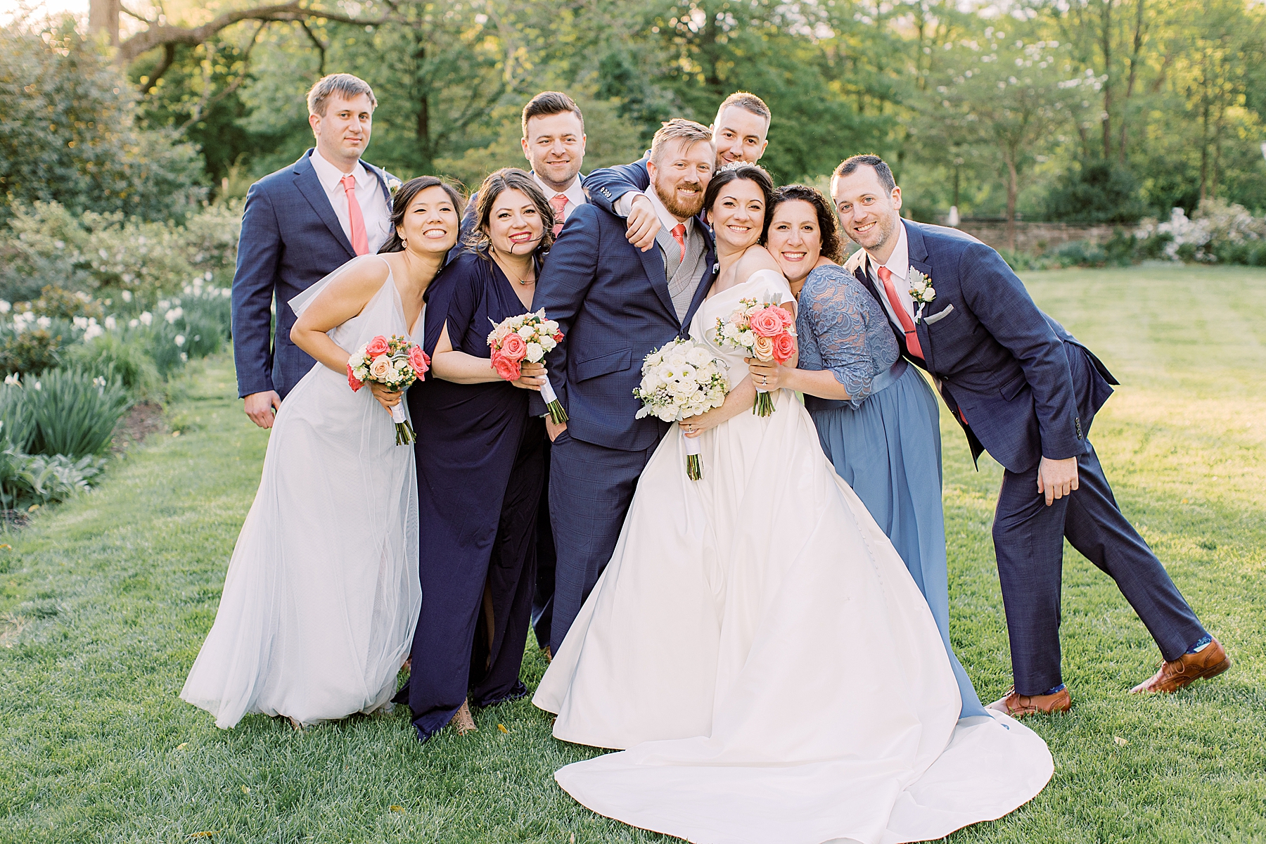 newlyweds pose hugging bridal party on lawn at Bellevue Hall