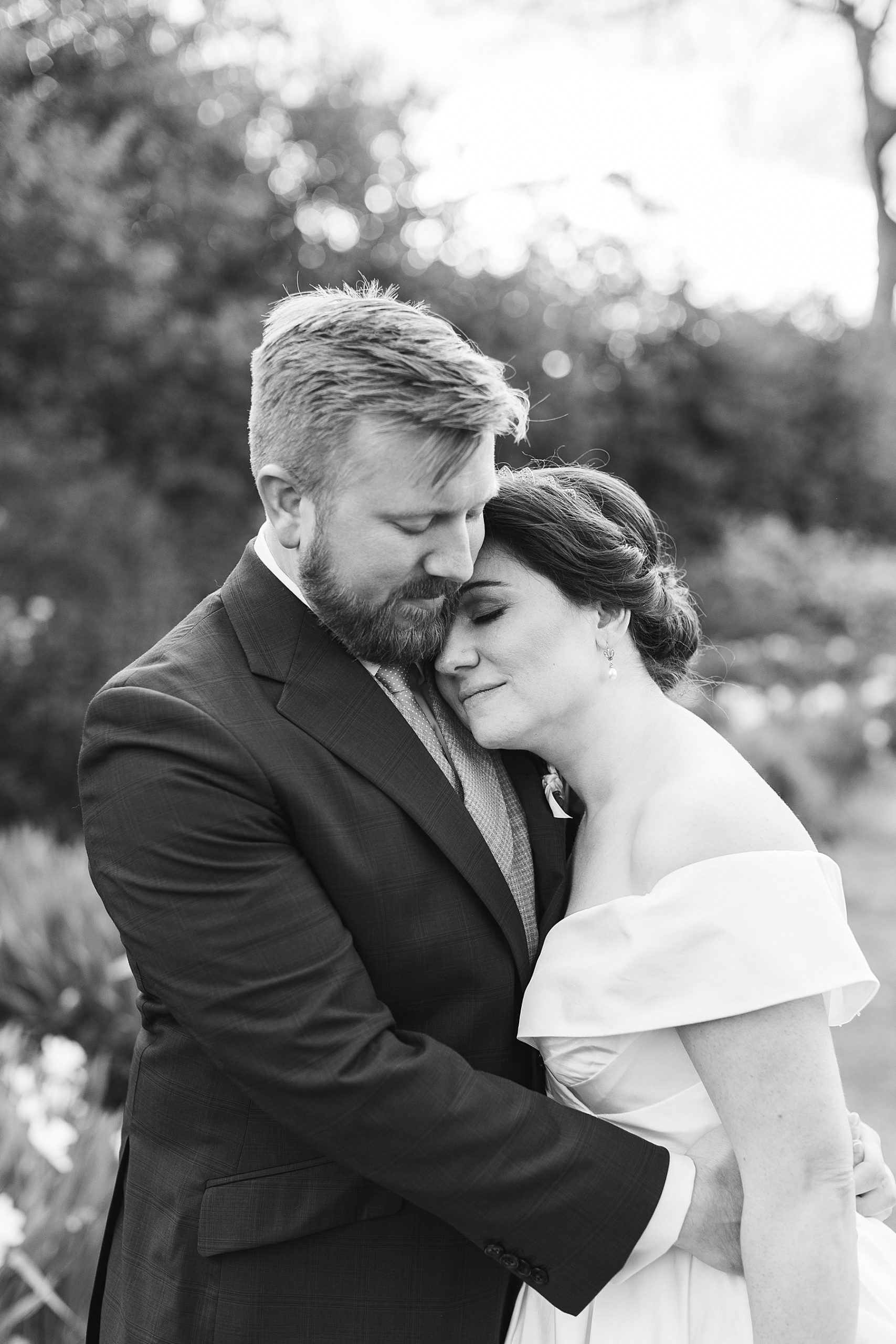 bride lays head on groom's chest in black and white photo 