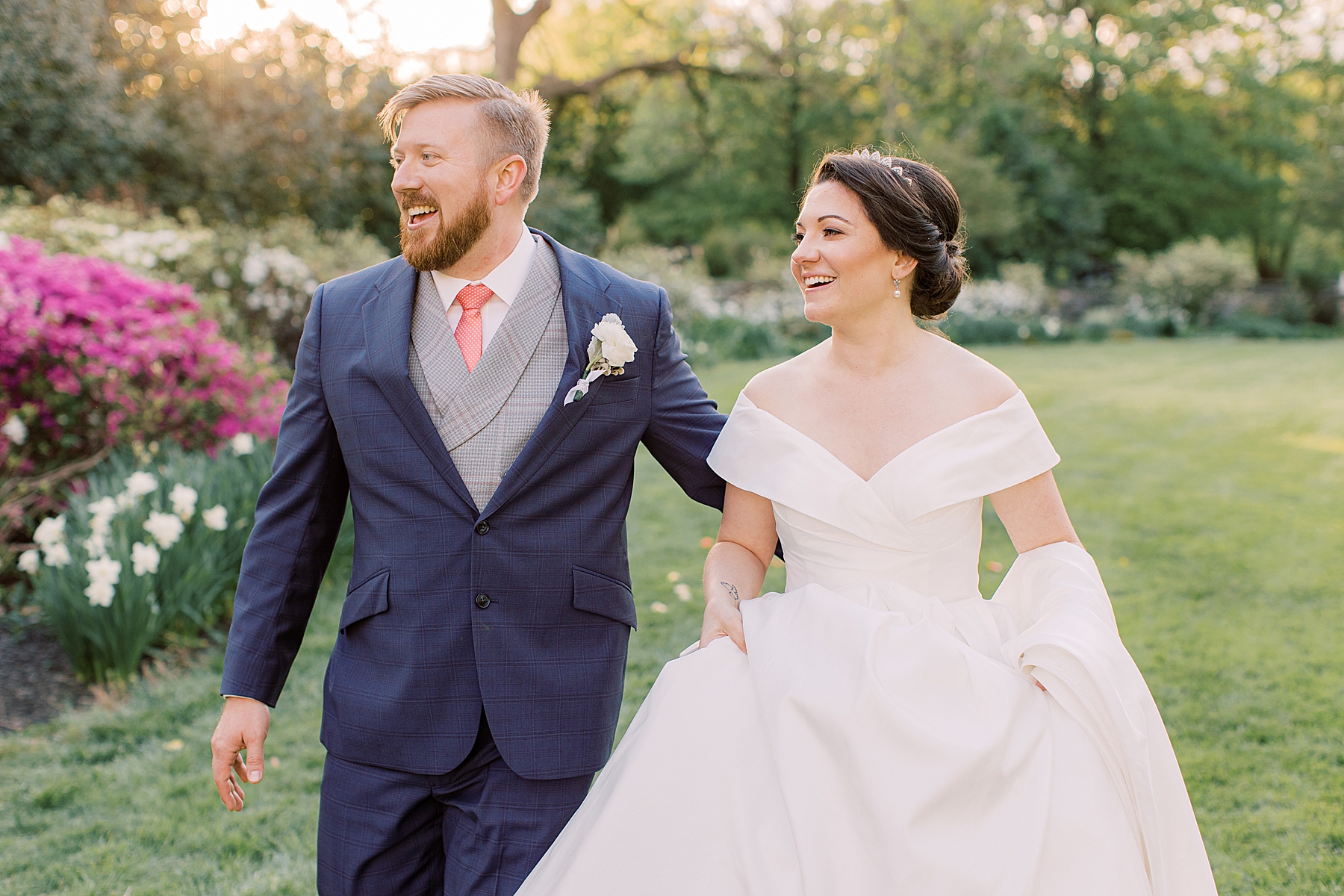 groom in navy suit walks with bride in off-the-shoulder classic wedding gown