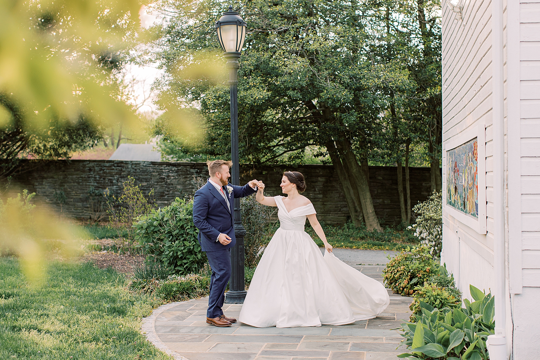 groom twirls bride in wedding dress on stone patio at Bellevue Hall