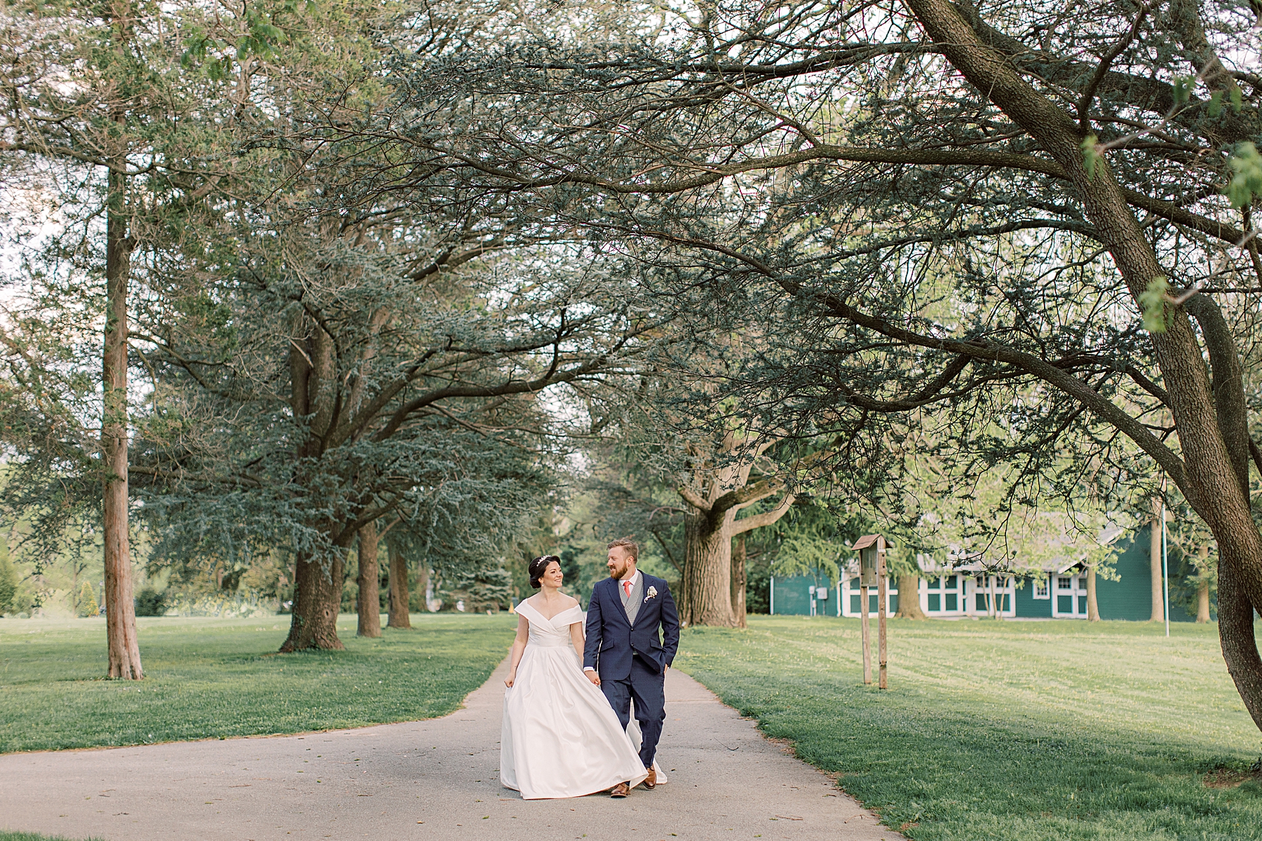 bride and groom hold hands walking through path at Bellevue Hall
