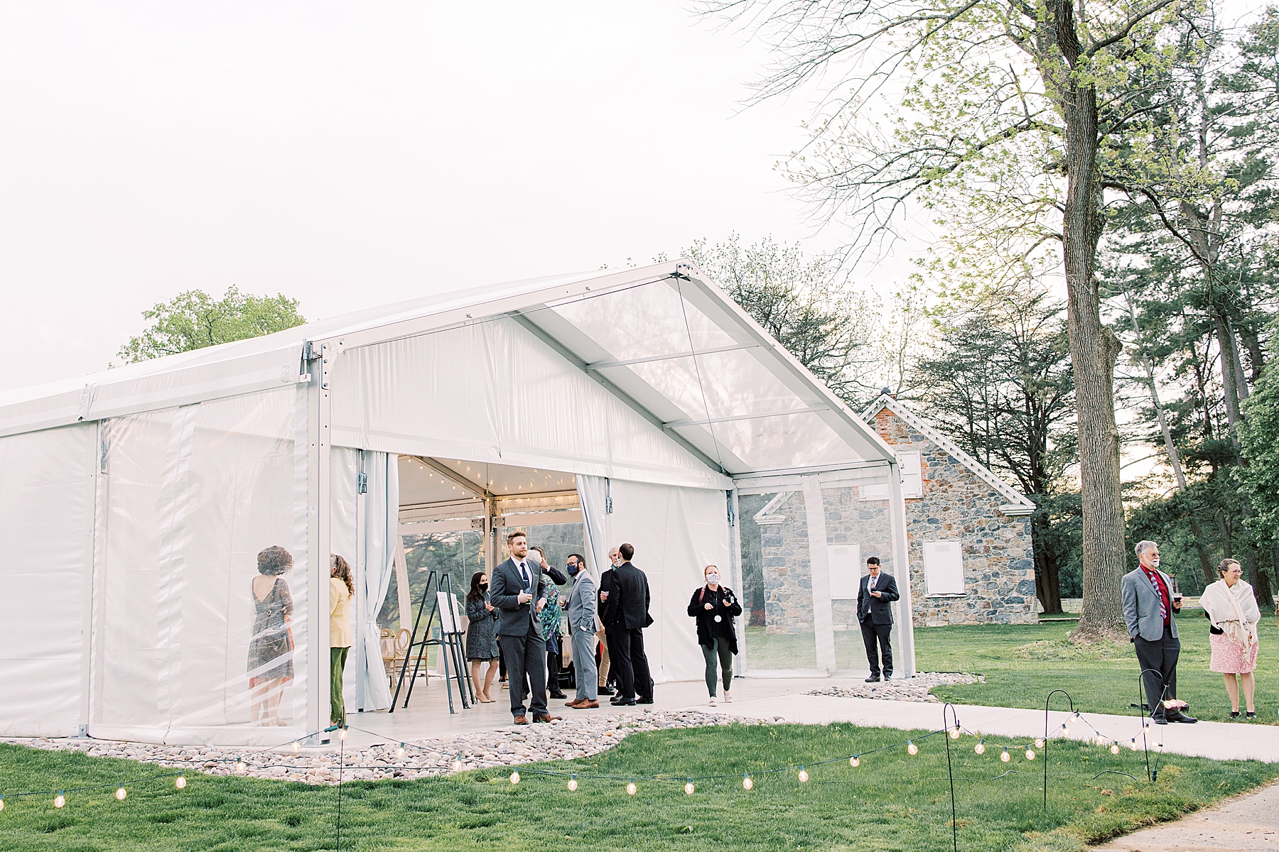 guests mingle outside tent at Bellevue Hall wedding reception 