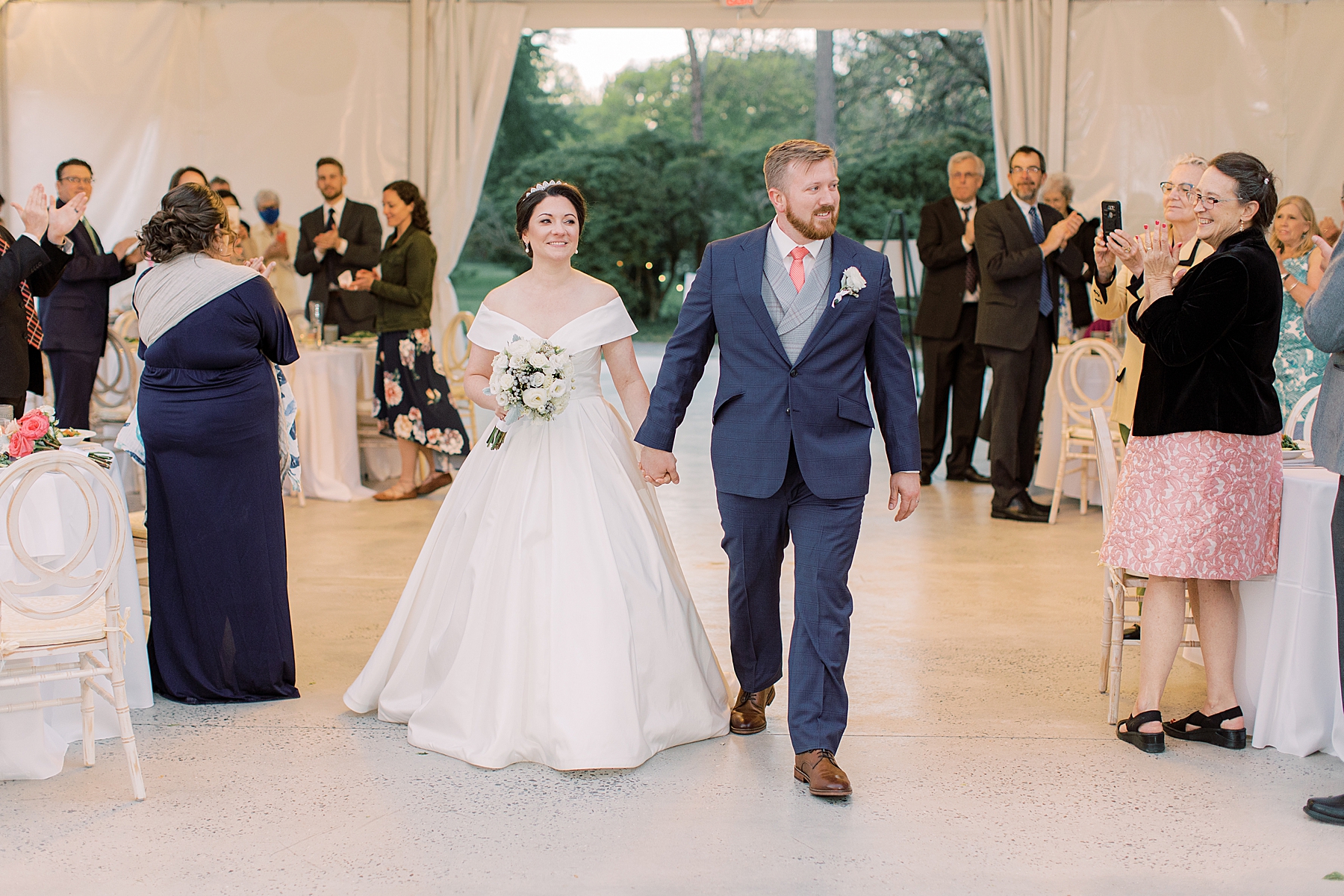 bride and groom hold hands walking into Bellevue Hall wedding reception