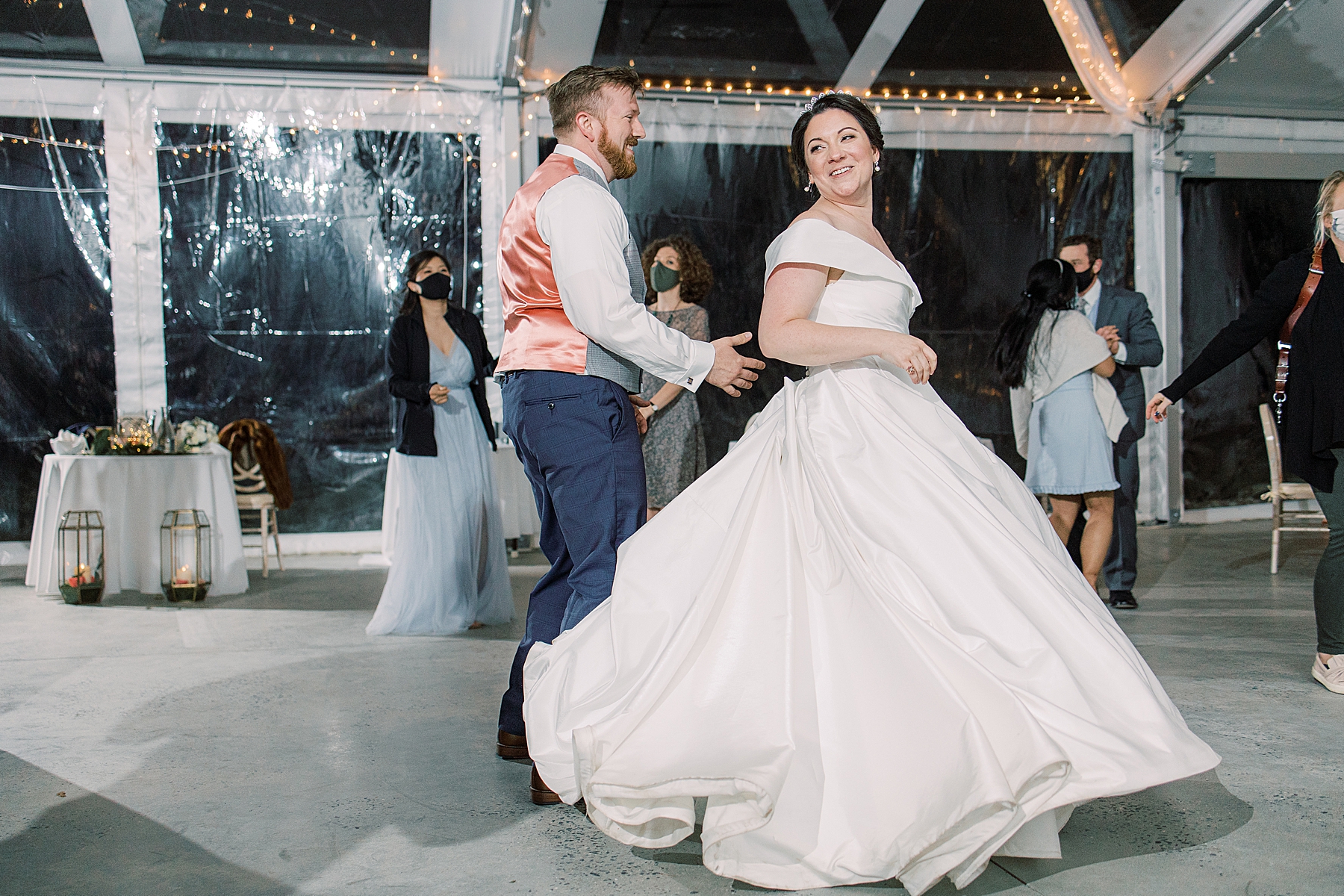 bride and groom dance with guests during tented wedding reception 