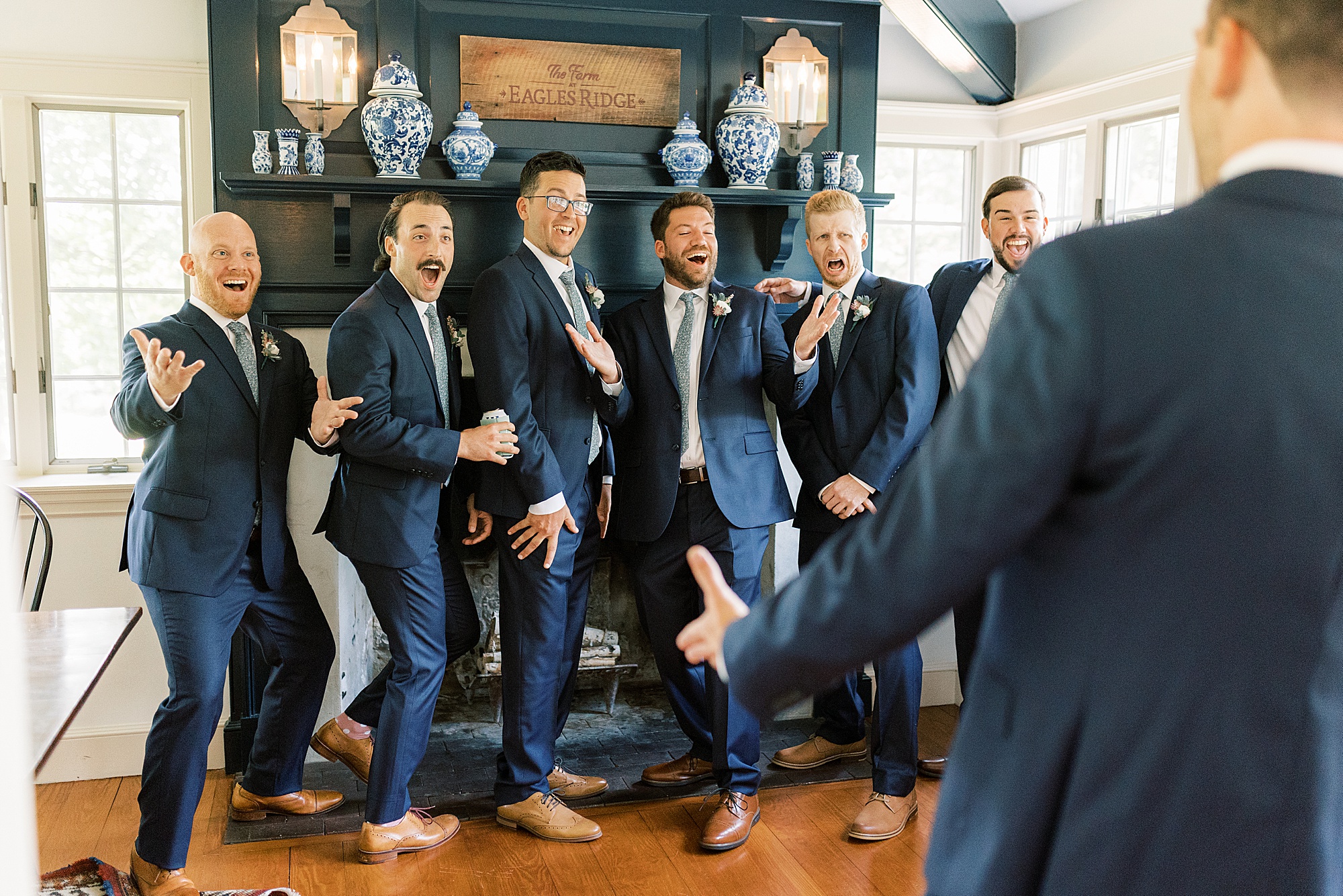 groomsmen smile and cheer during first look with groom at The Farm at Eagles Ridge 