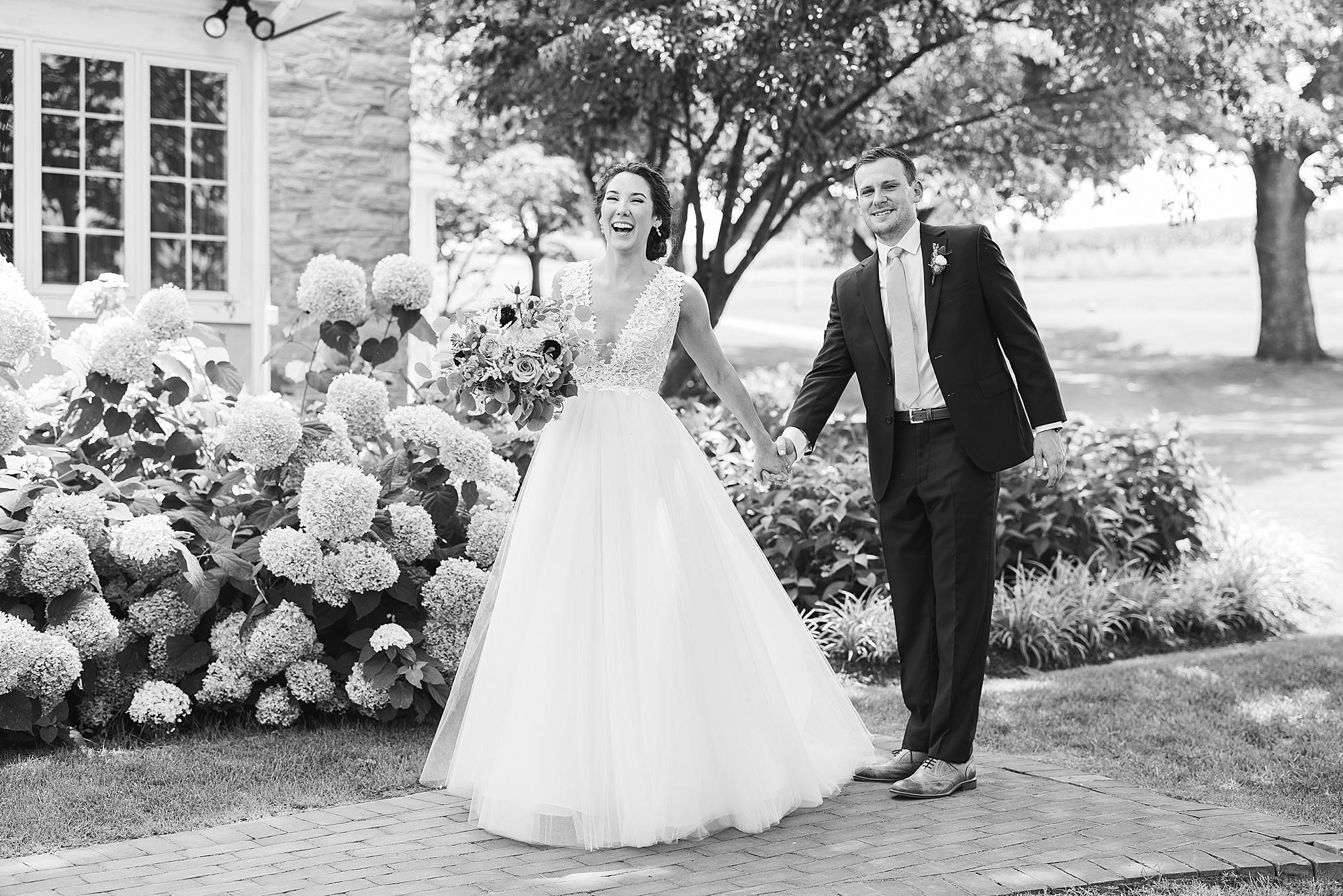 bride and groom laugh walking on pathway together at The Farm at Eagles Ridge 