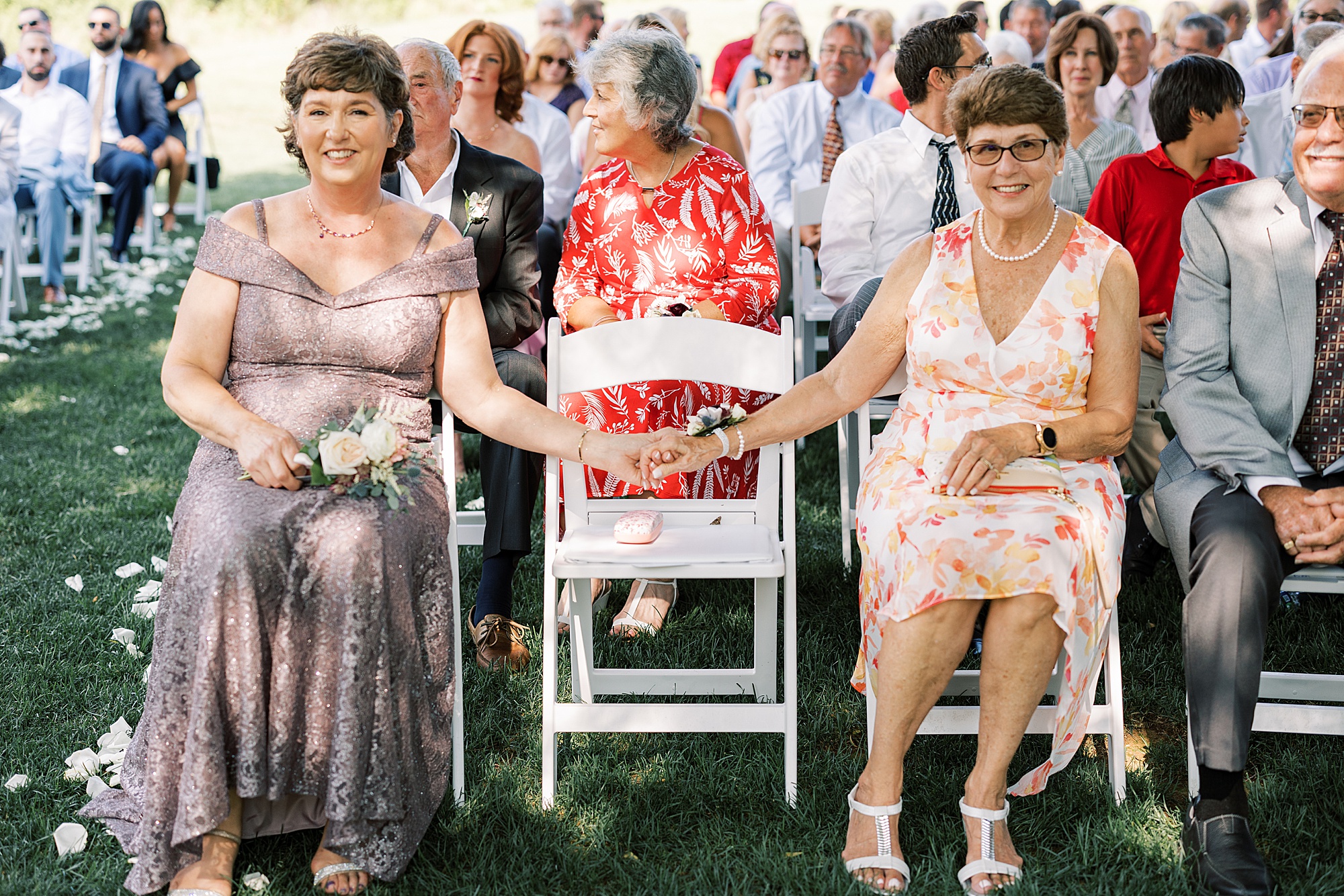 women hold hands smiling during wedding ceremony 