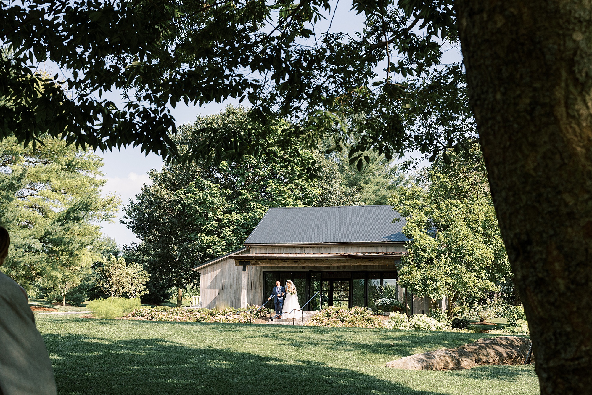 bride walks out of building with father at The Farm at Eagles Ridge 