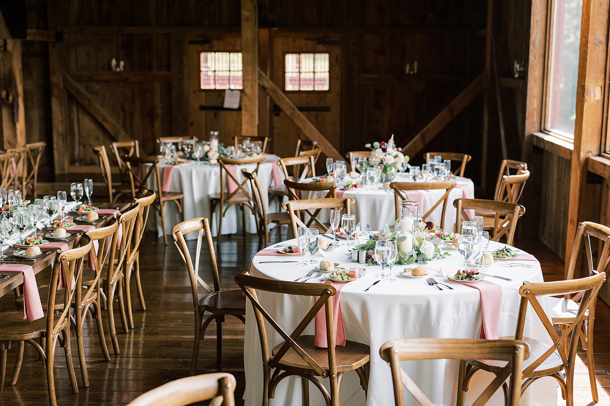 barn wedding reception with candle centerpieces and pink napkins 