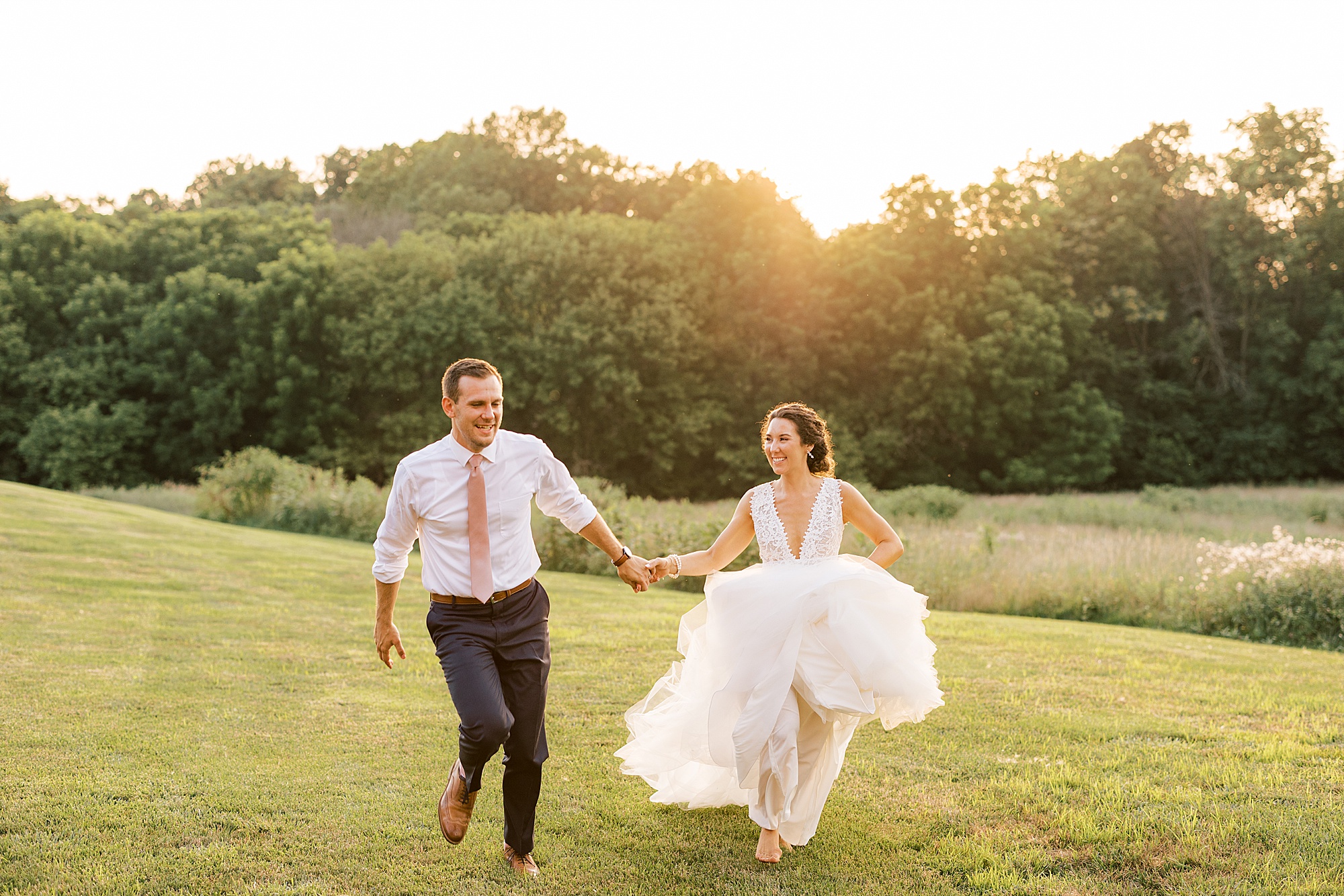 bride runs on lawn barefoot with groom at The Farm at Eagles Ridge
