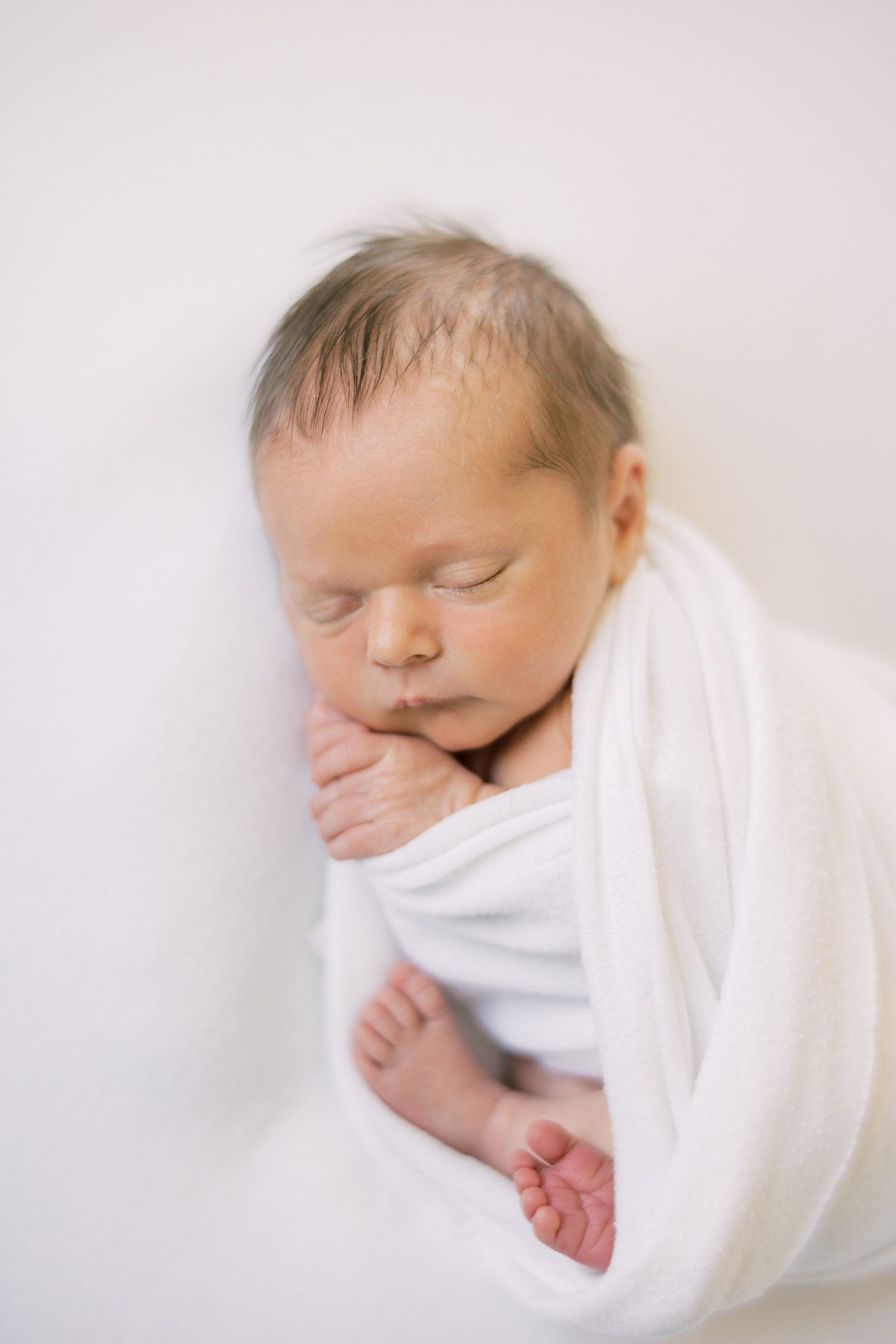 sleeping newborn baby in white wrap 