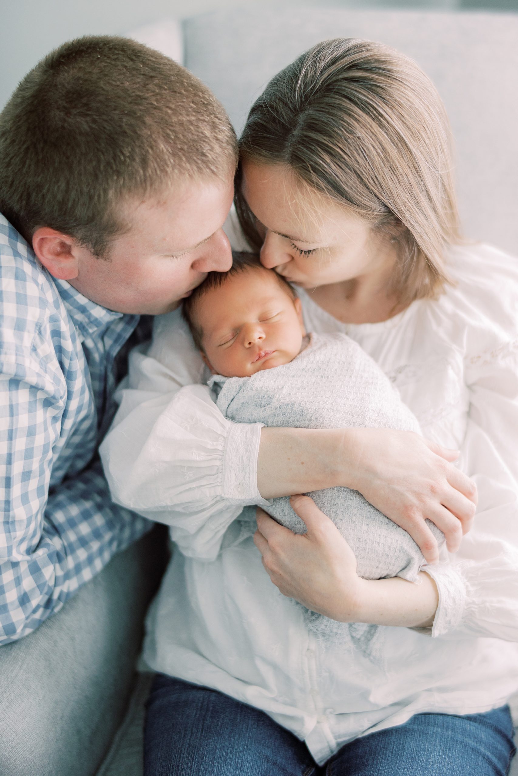 Fine Art Film Inspired image of a mother and father with their newborn baby in neutral tone clothing photographed by Philadelphia Newborn Photographer Le Papillon by Samantha Jay