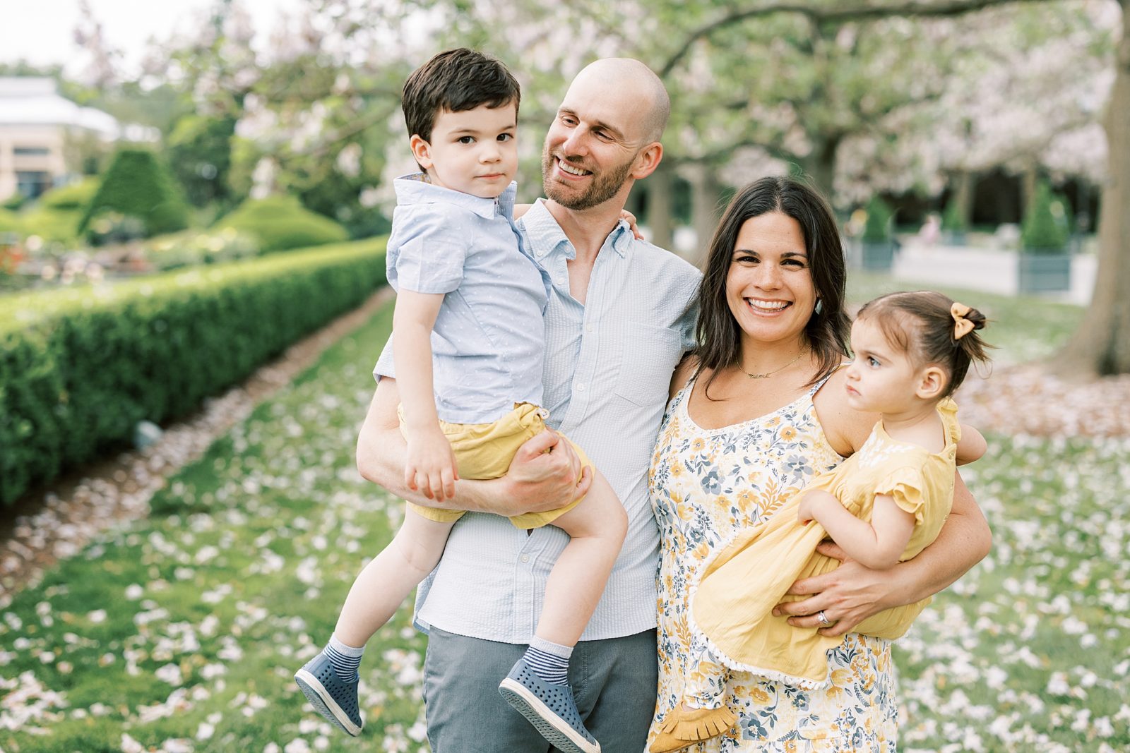 family of four hugs and smiles in yellow and blue outfits for spring photos 