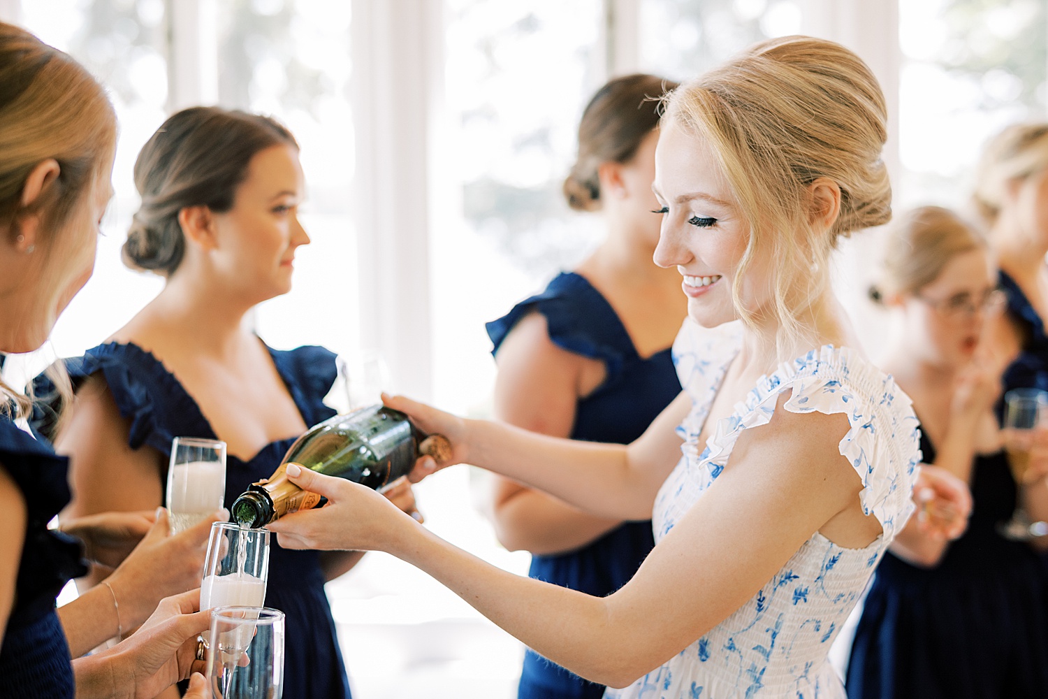 bride with updo pours champagne for bridesmaids 