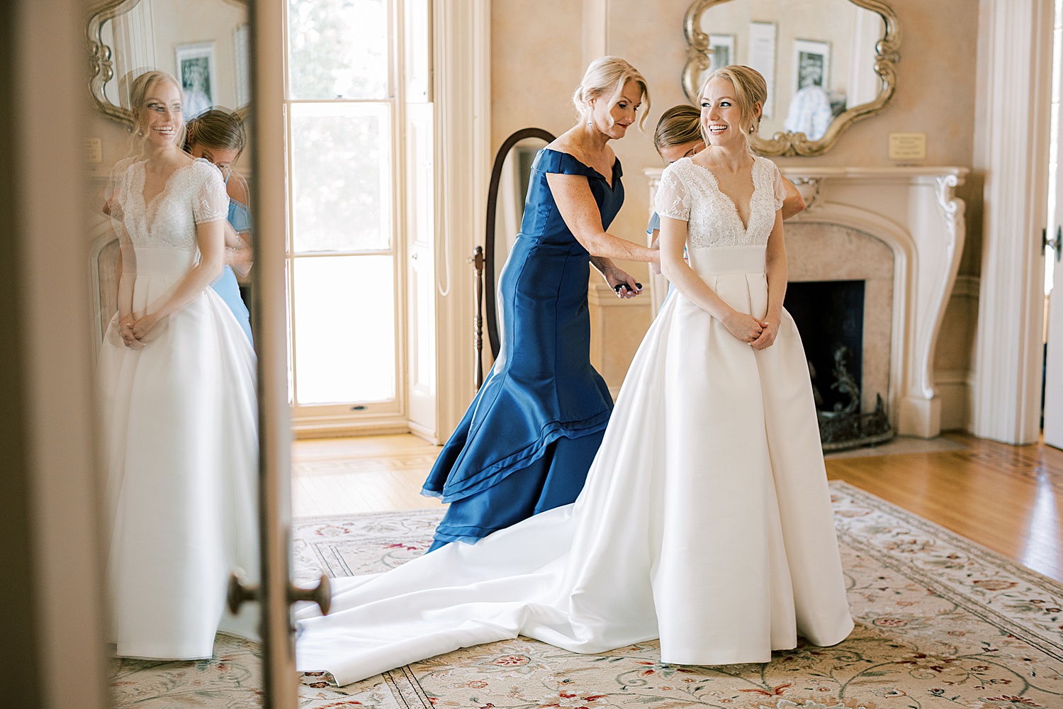 mother in navy gown helps bride into classic wedding dress 
