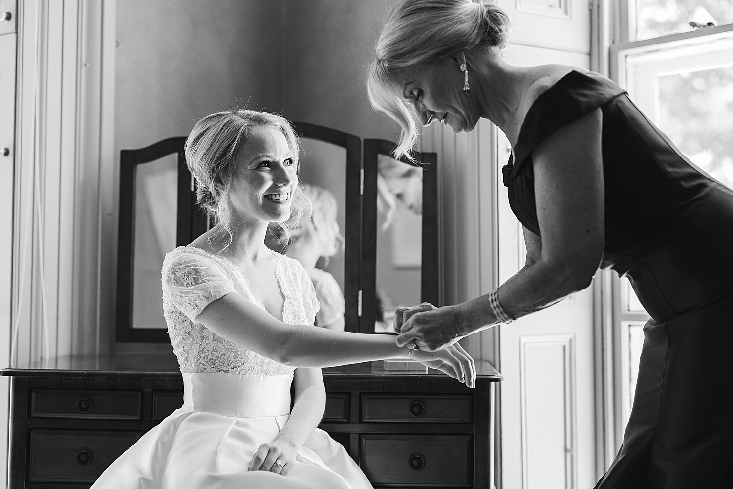 black and white portrait of mother helping bride with bracelet 