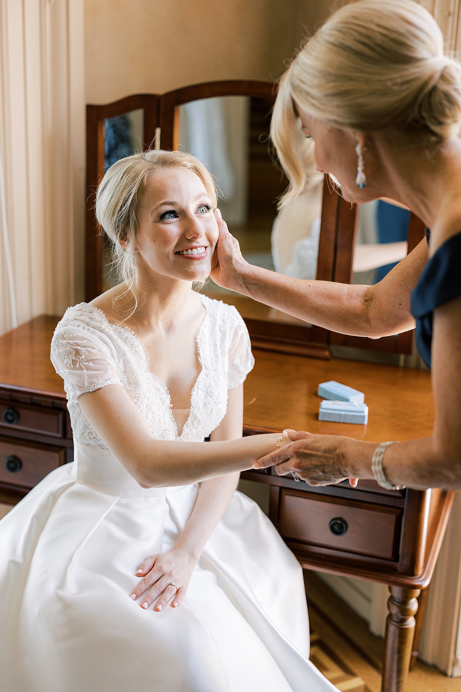 mother holds bride's cheek smiling at her before wedding day at 