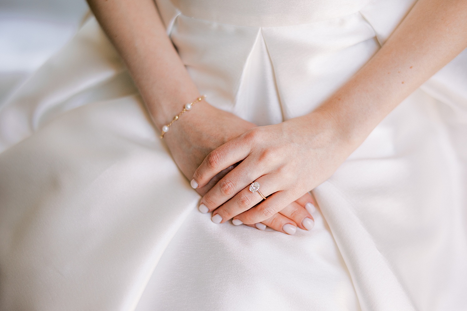 bride sits with hands folded in lap showing off diamond ring 