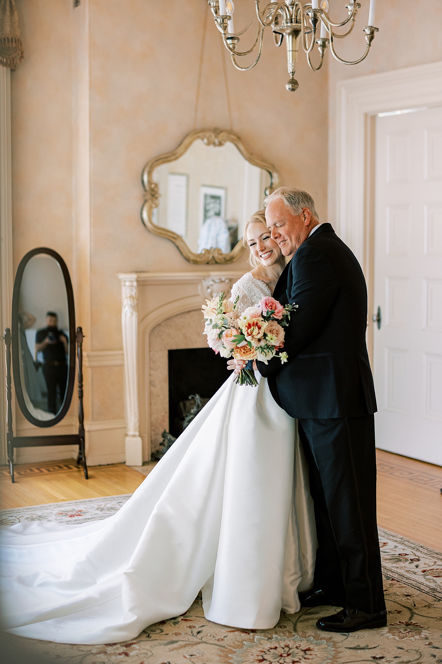 bride hugs dad in wedding gown with bouquet of pink and peach flowers 