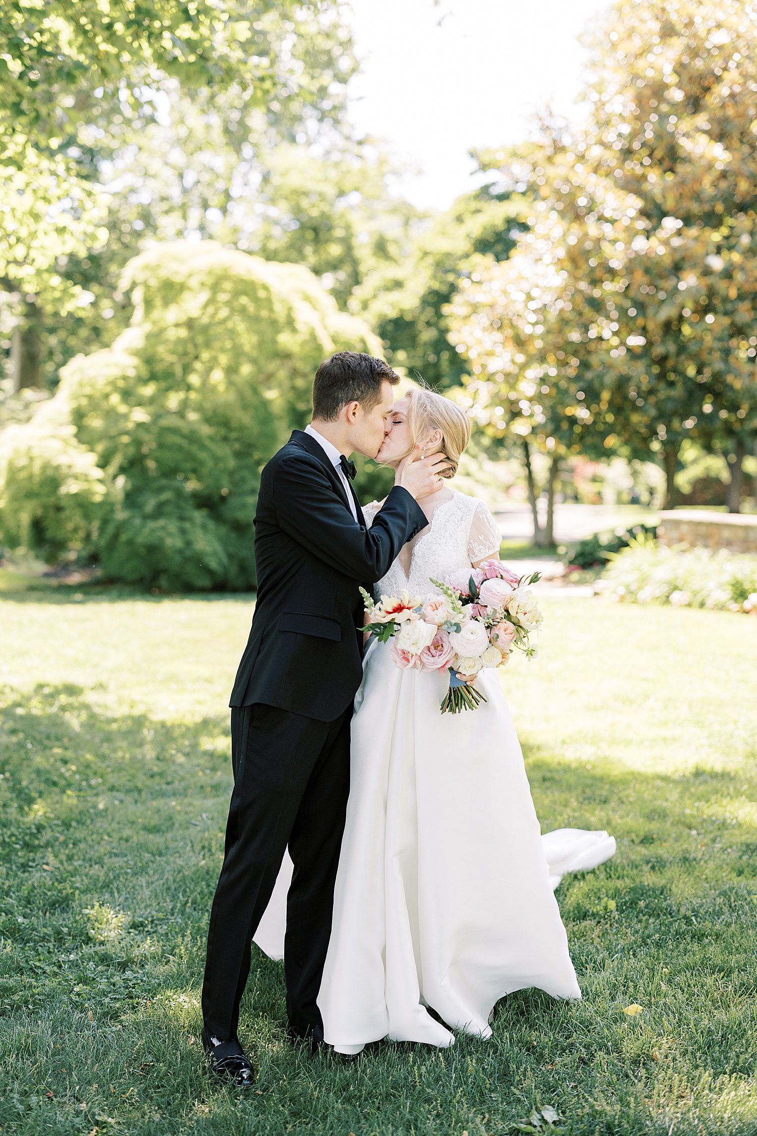 bride and groom kiss during summer wedding portraits 