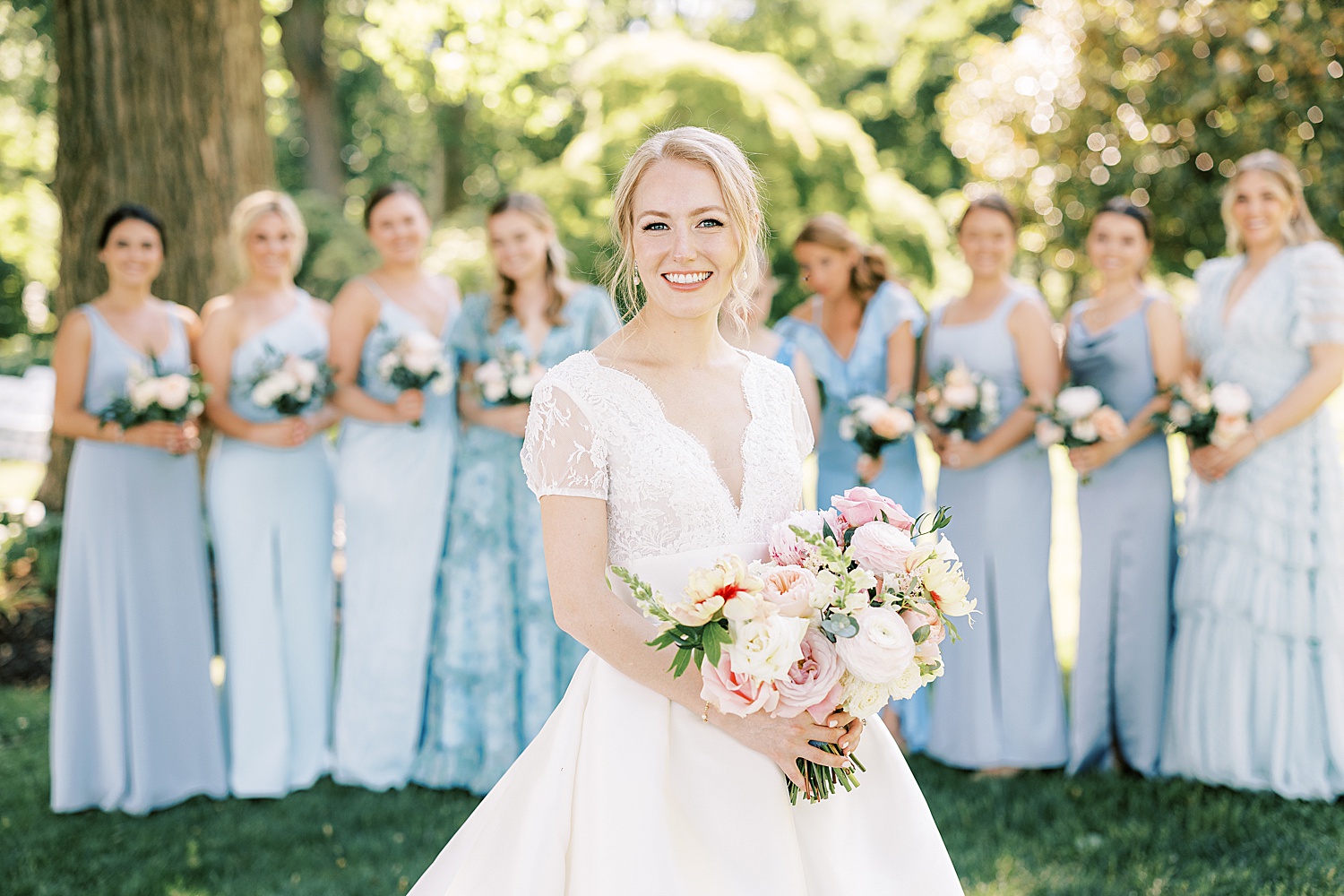bride stands in front of bridesmaids in blue gowns 