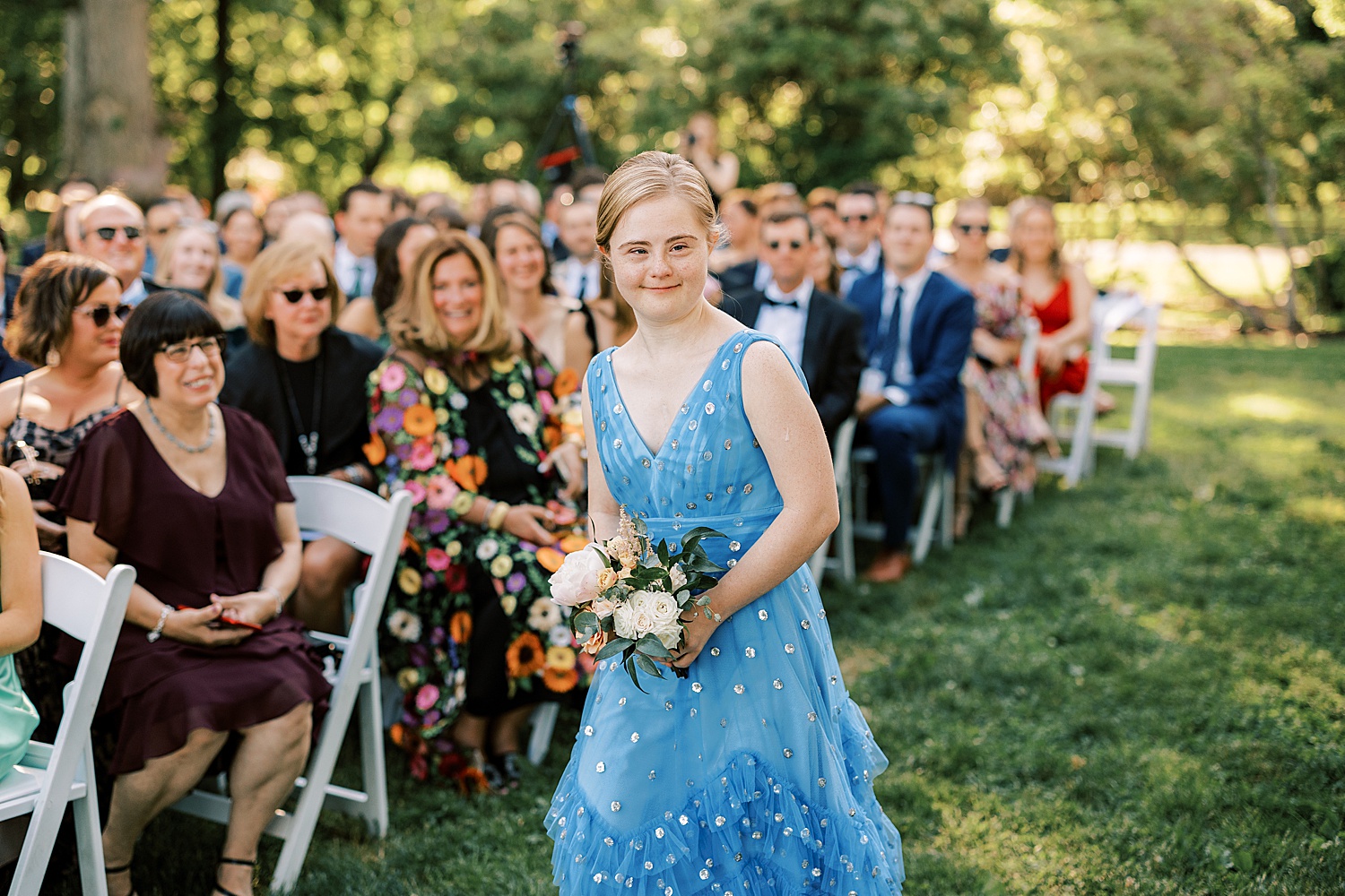 young woman with down syndrome holds summer bouquet and walks down aisle 